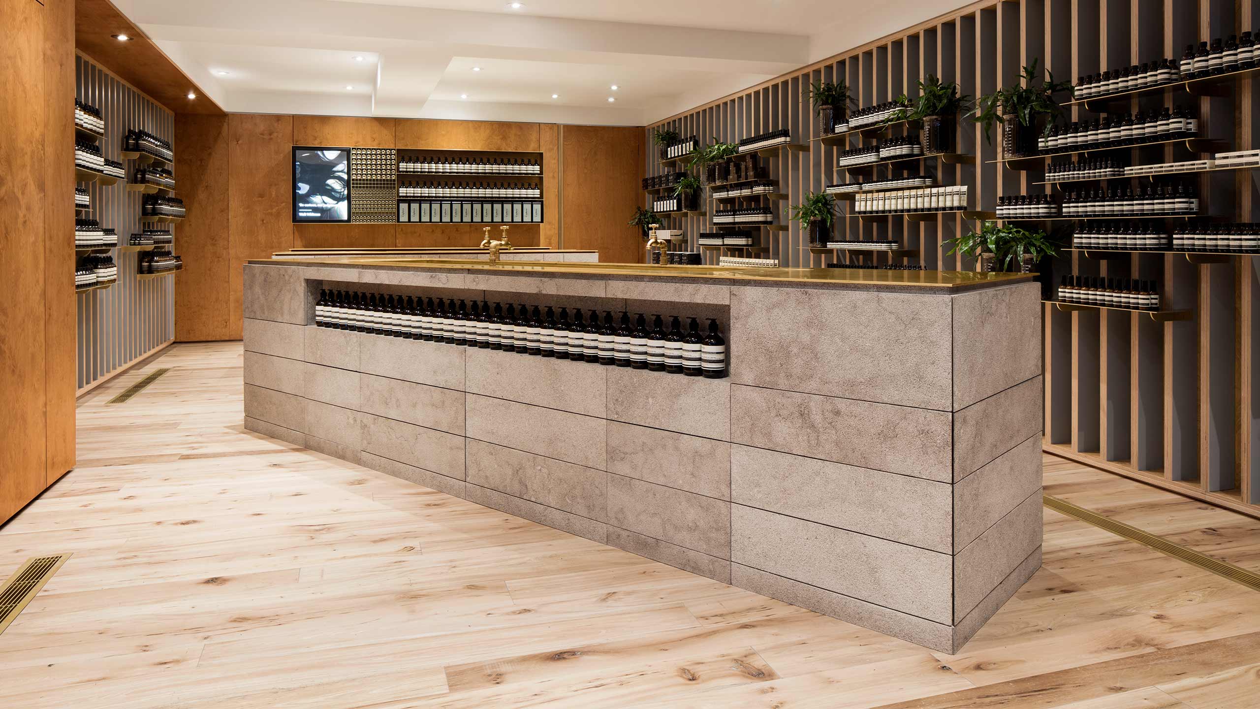 A large rectangular limestone sink sits at the centre of space holding Aesop tester bottles