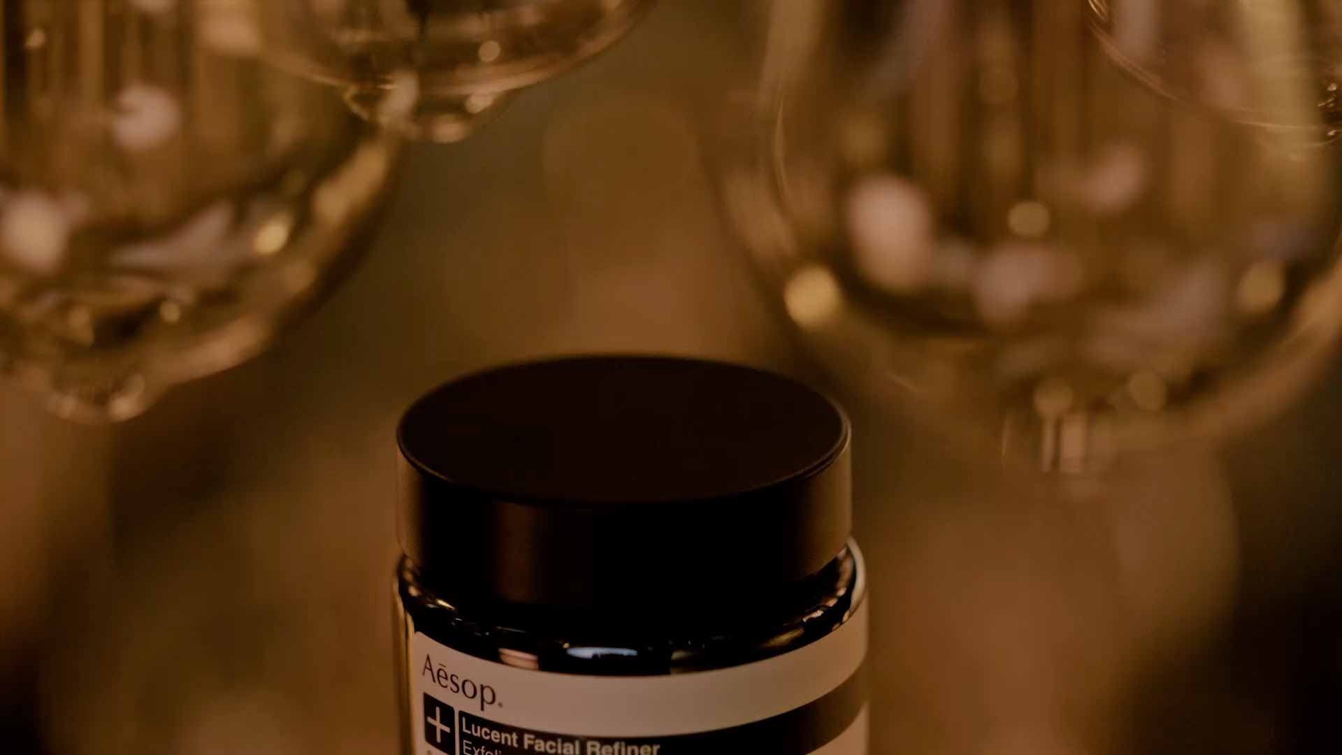 Light bulbs surrounding a jar of Lucent Facial Refiner.