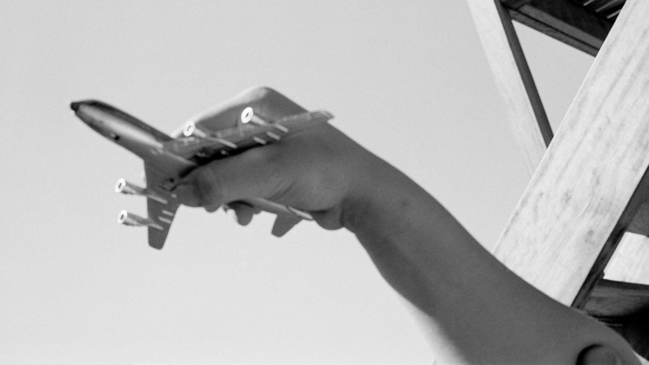 Greyscale image of a toy plane being held by a hand.