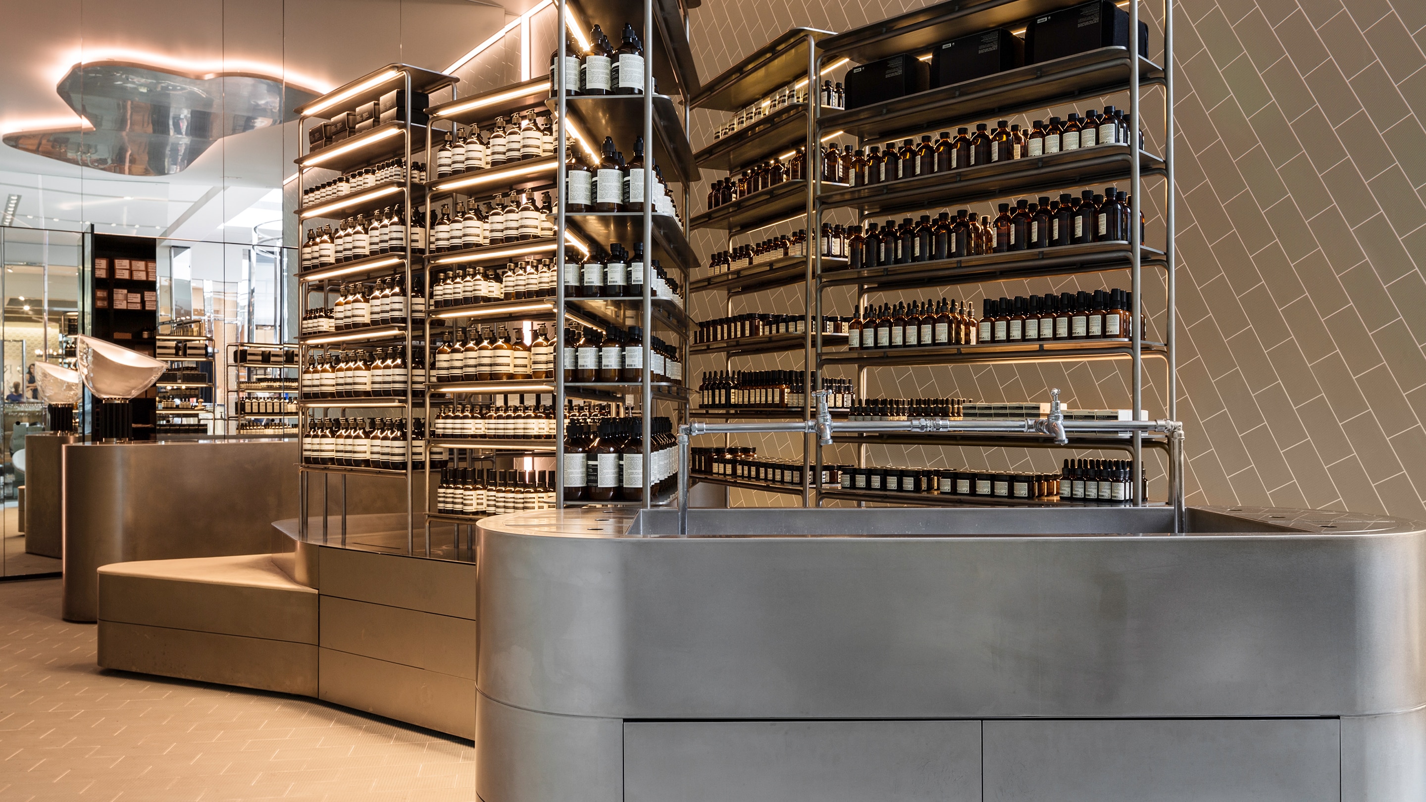 Brushed steel customer service basin in the center of the store surrounded by shelving constructed out of steel pipes.