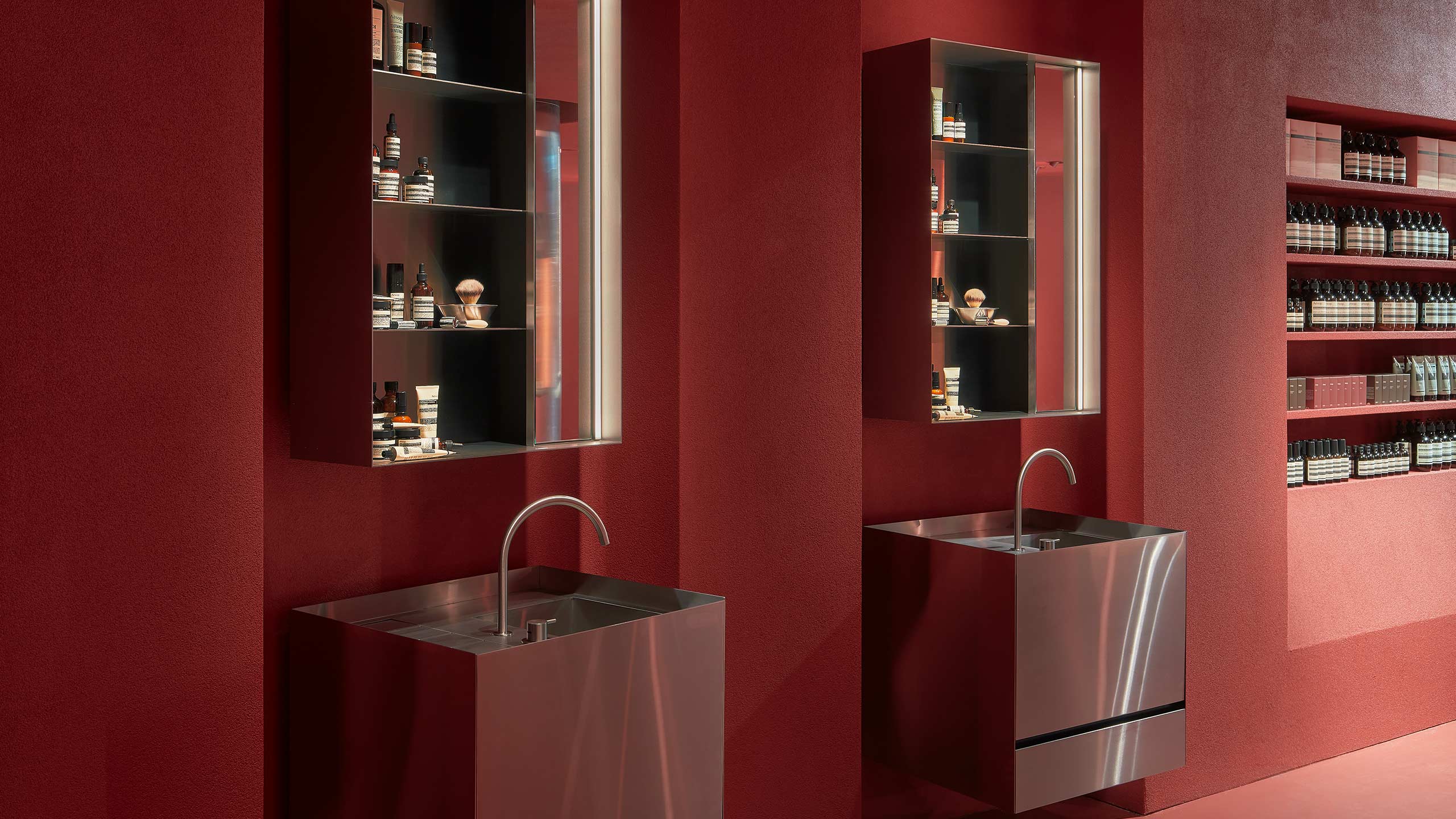 Two customer service basins are lining the dark red wall.