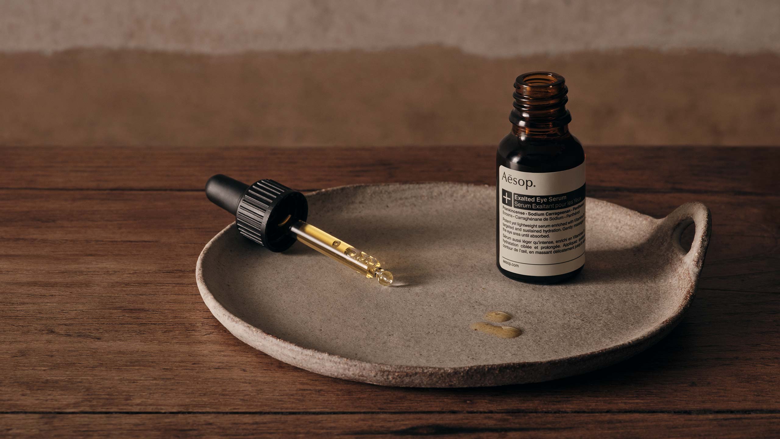 A ceramic plate and a bottle of exalted eye serum placed on a wooden surface