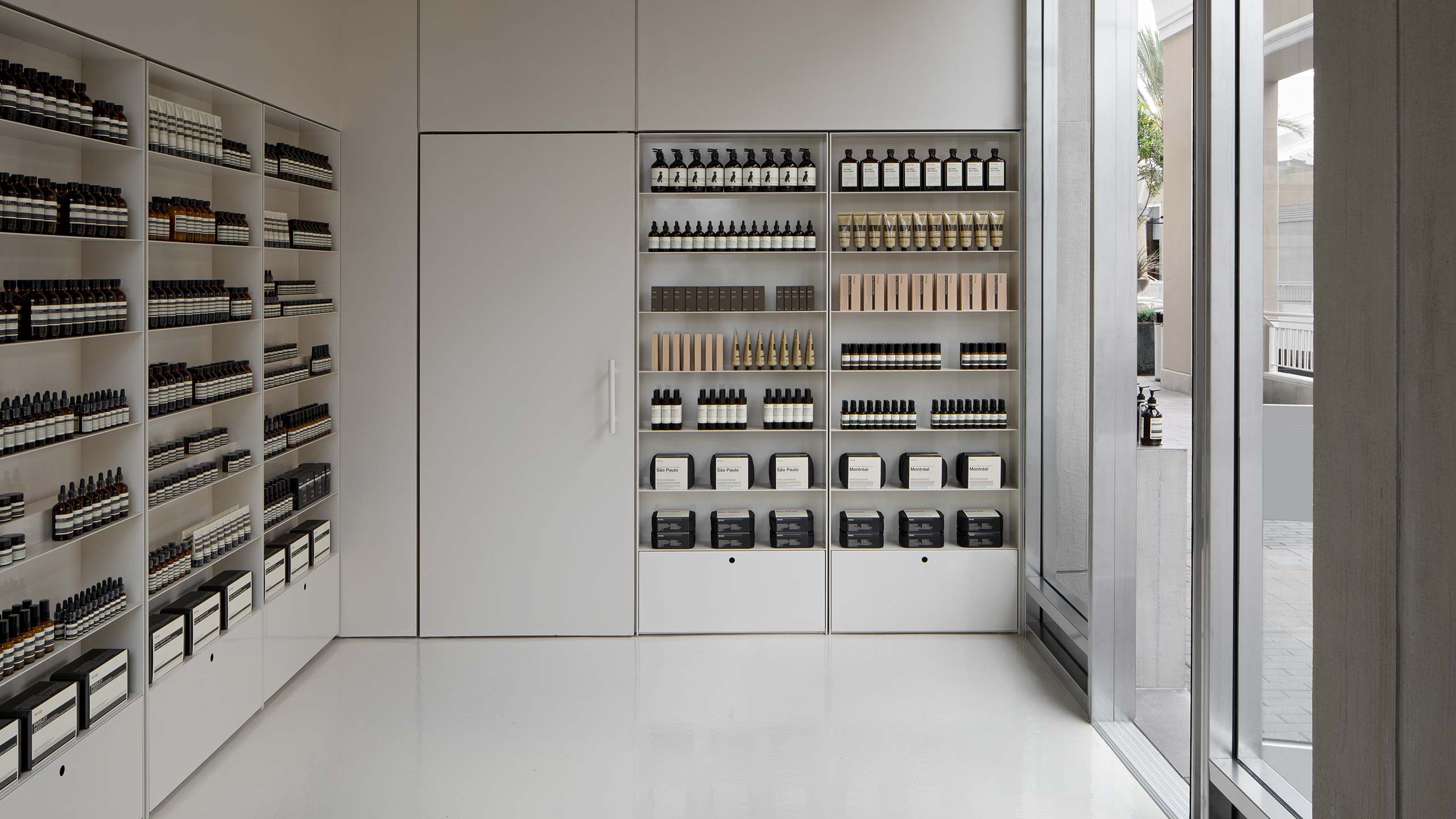Taupe coloured flooring with soft and white shelving holding Aesop product.