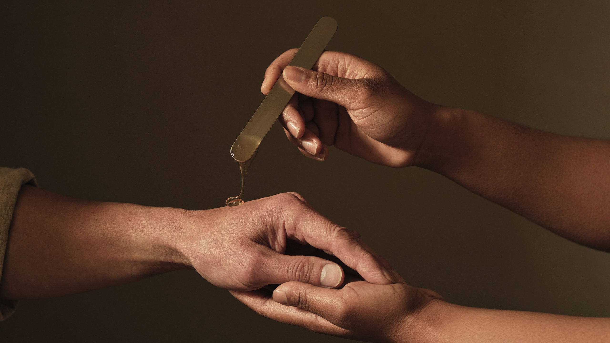A hand using metal spatula to apply b triple c on other hand