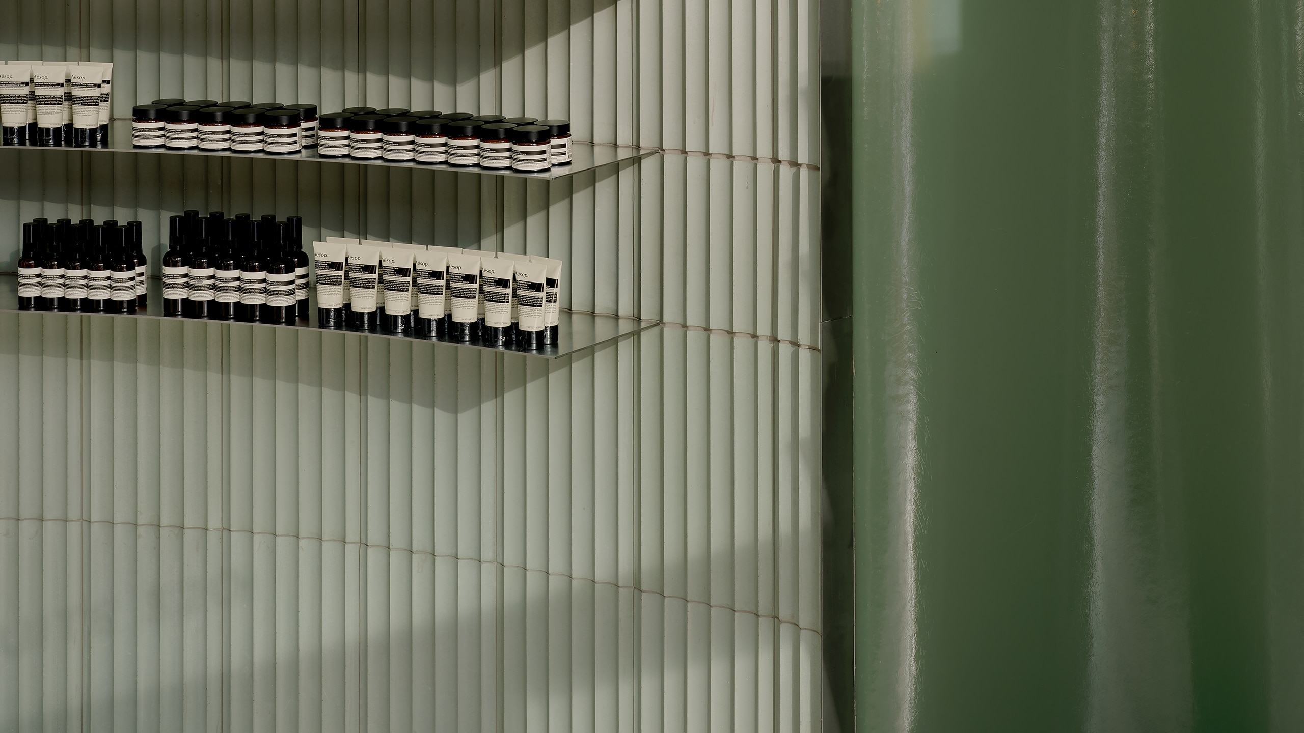 grey corrugated wall lined with product on shelves