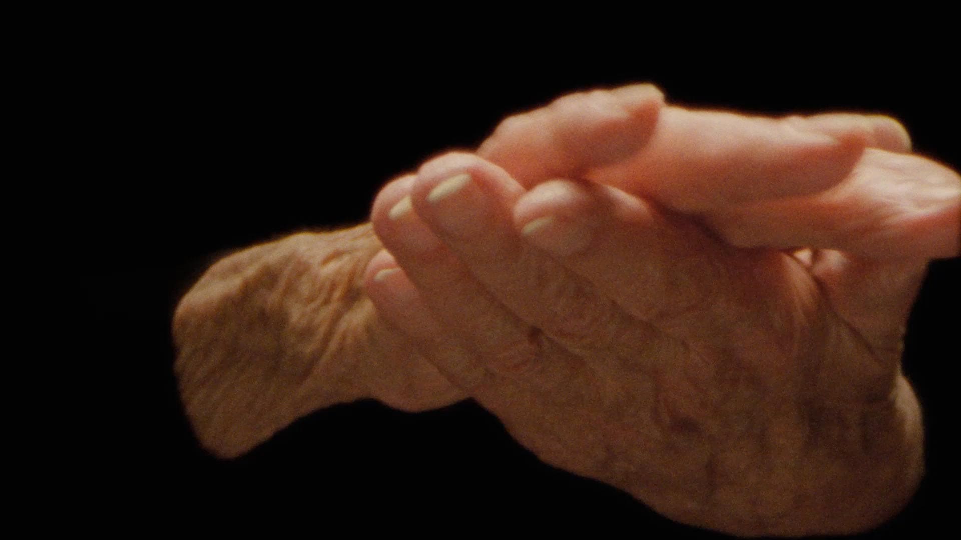 Isolated hands on a black background rubbing balm into each other.