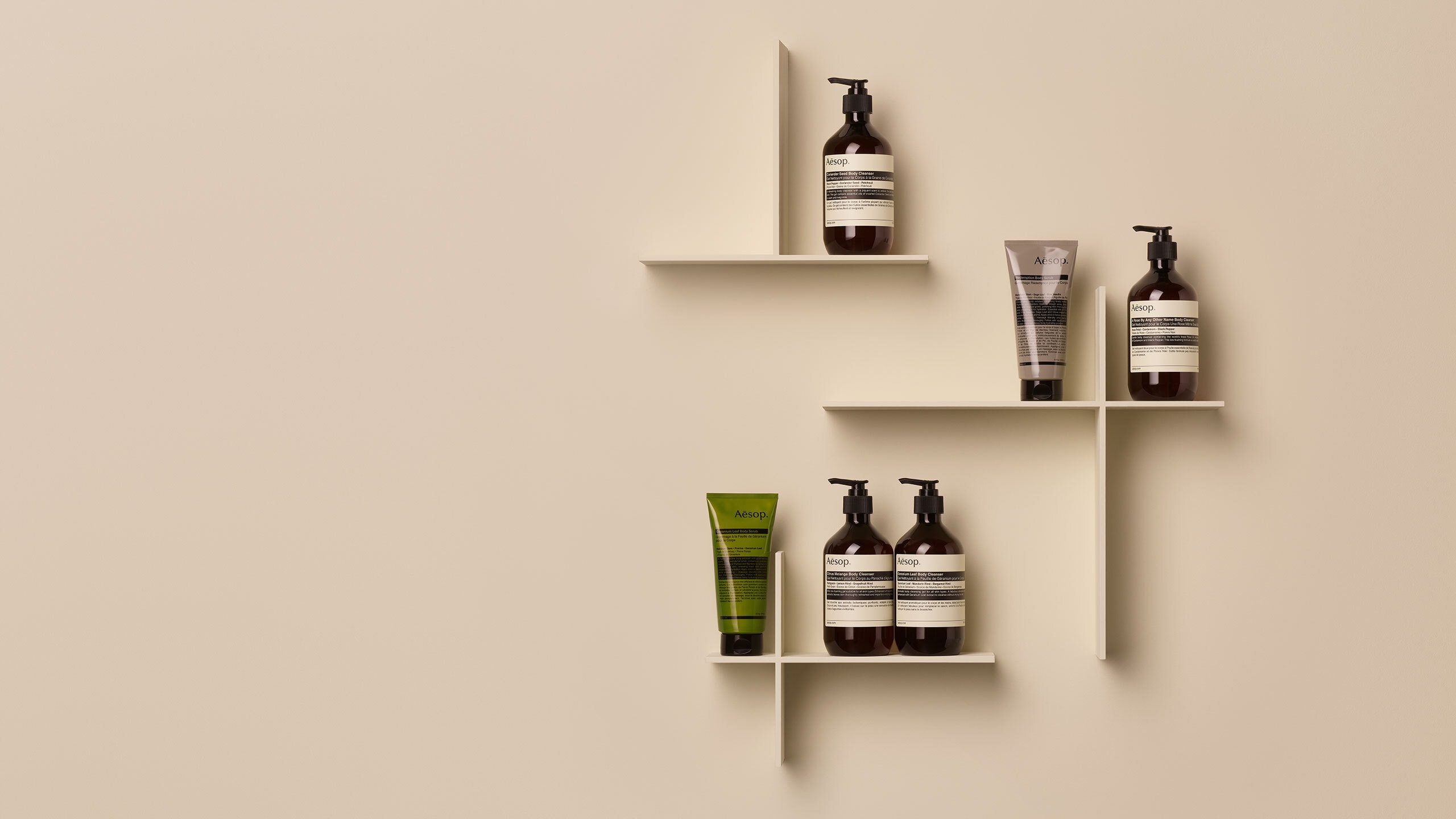 Aesop body cleansers in brown bottles with a yellow and orange background