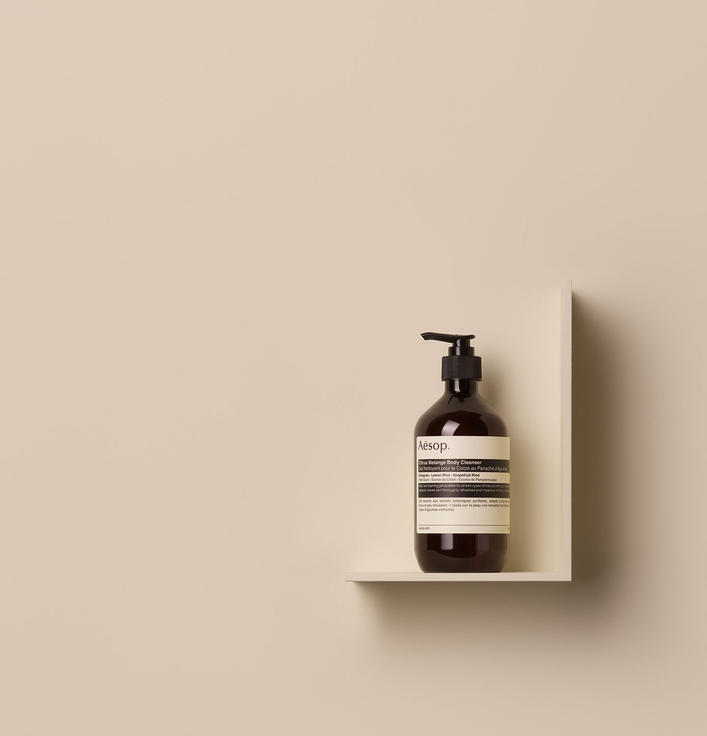 Aesop Citrus Melange Body Cleanser in 500ml amber bottle with pump, placed on a shelf in a beige background