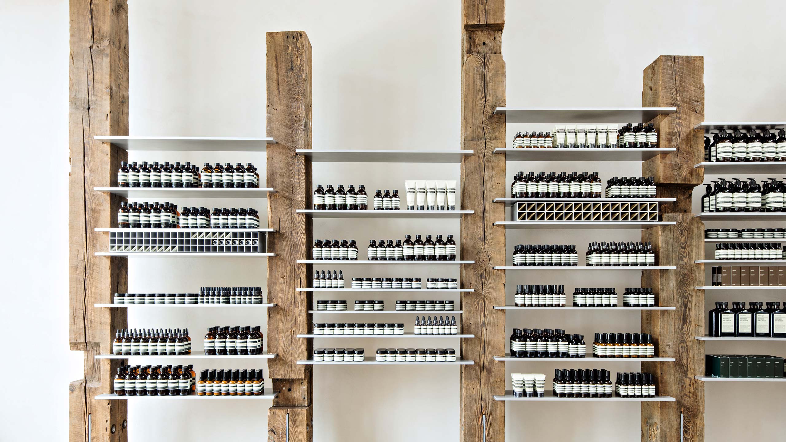 Wooden beams framing steel shelves; holding Aesop product