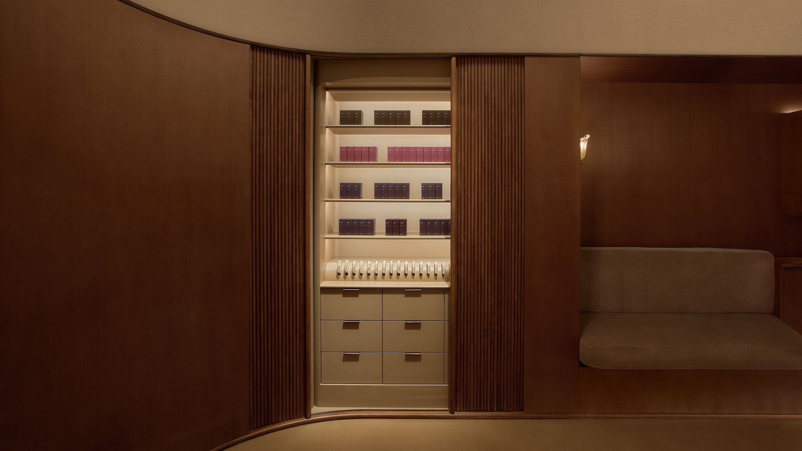 A Fragrance Armoire hidden in the curved wall, contains Aesop’s range of nonconformist Eaux de Parfum, with a velvet sofa aside.