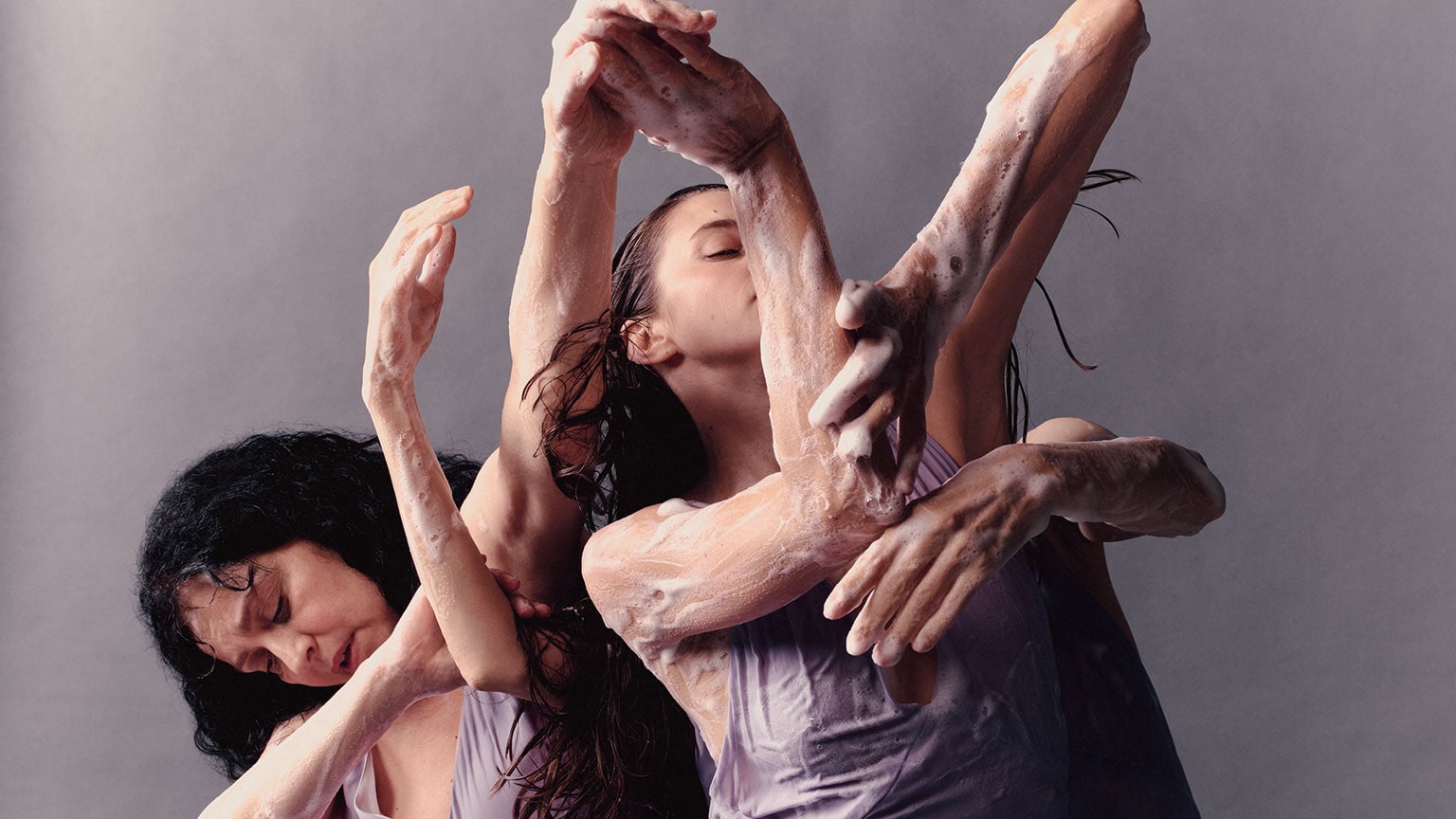 Dancers wearing purple dress dancing in a purple background