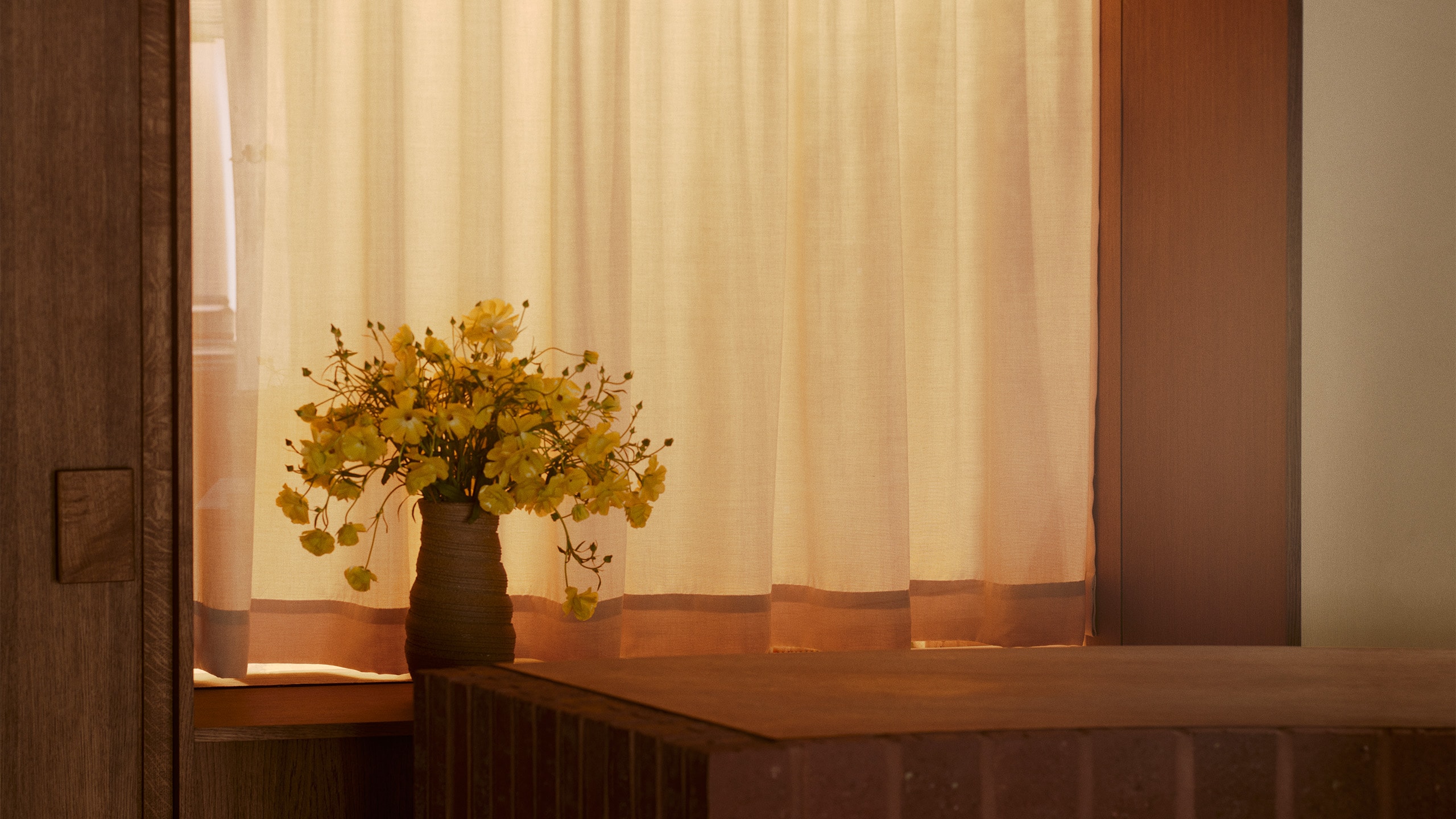 Aesop Kronprinsensgade store single flower arrangement placed within a vase, in front of a linen material curtain.