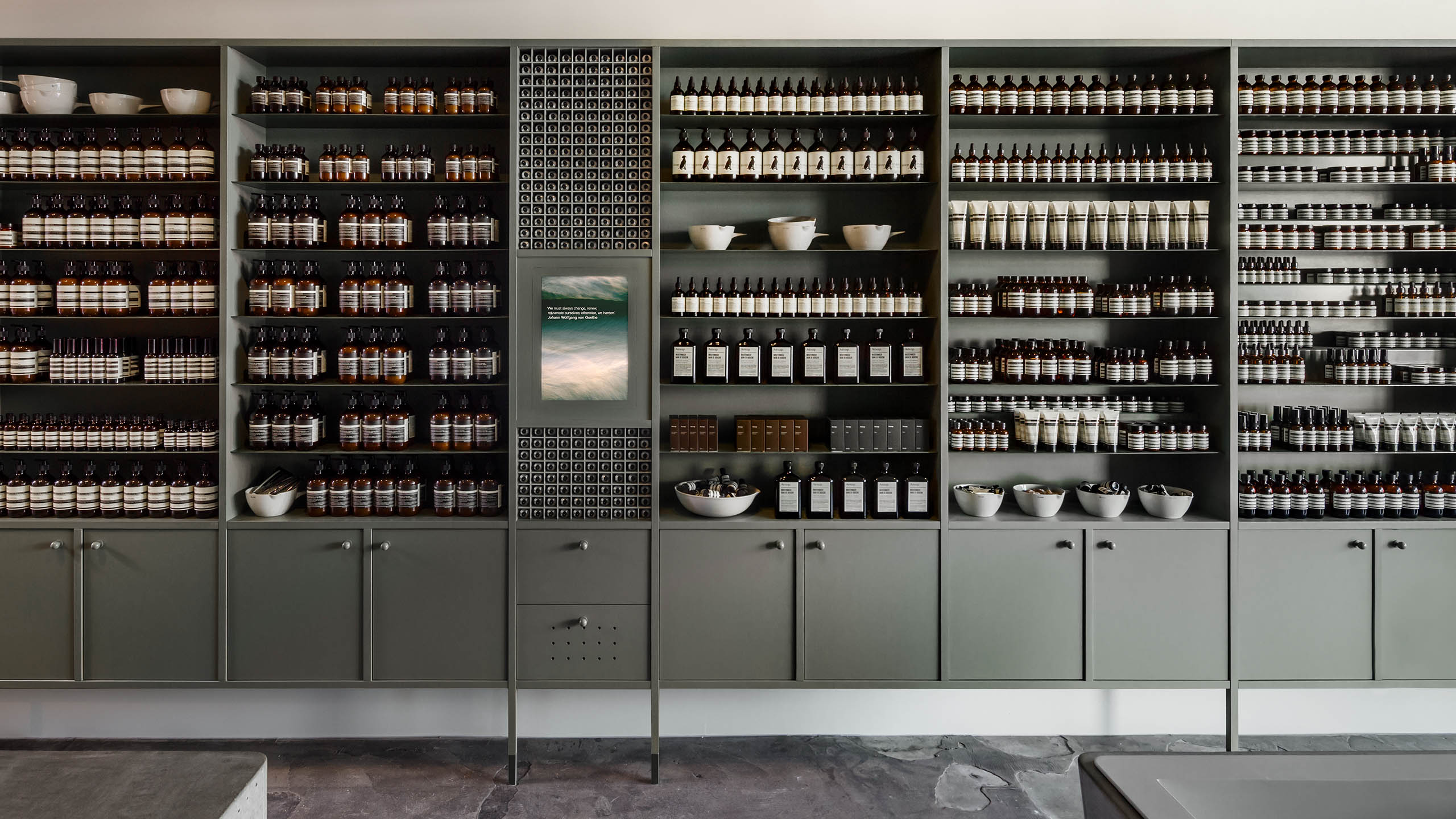 The traditional timber cabinets that have been hand-painted a soft green. Each shelf is stocked with several Aesop products.