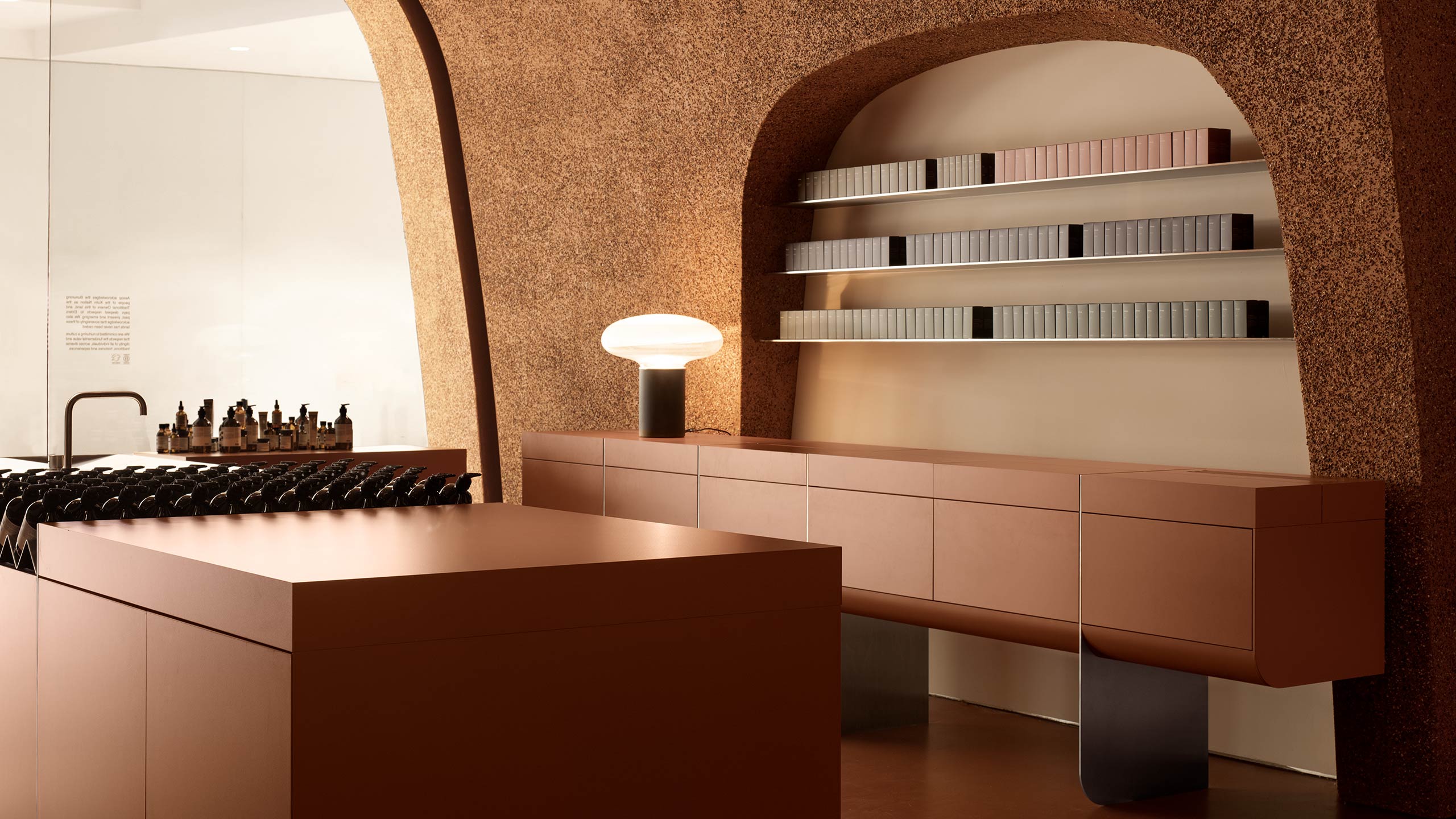 Aesop Southland interior showing Aesop fragrances placed on shelves next to a lamp on a benchtop