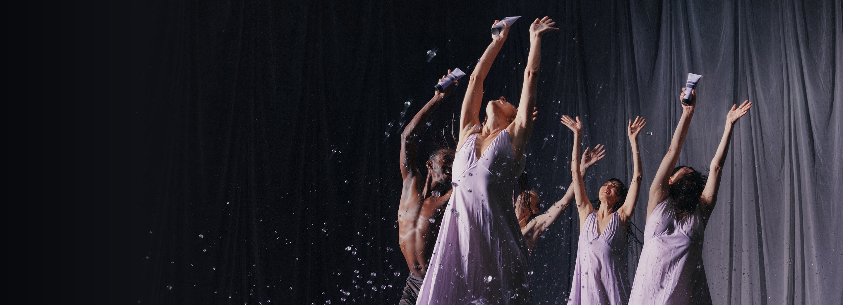 Dancers holding eleos nourishing body cleanser tubes and raising their hands