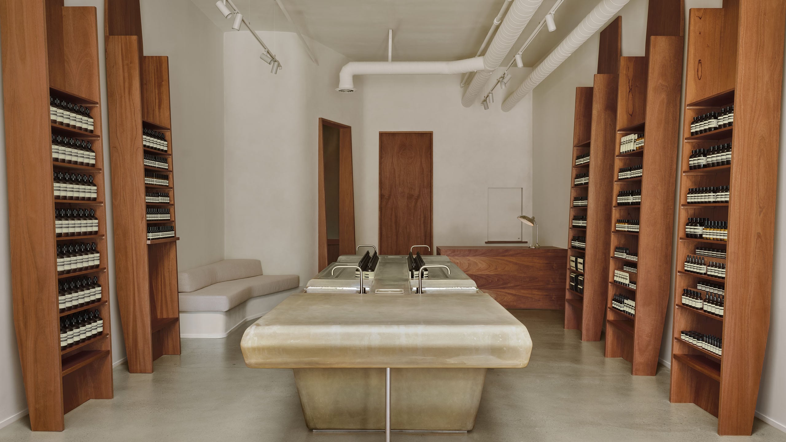 store interior shot featuring wooden product shelving units along white walls and center basin unit