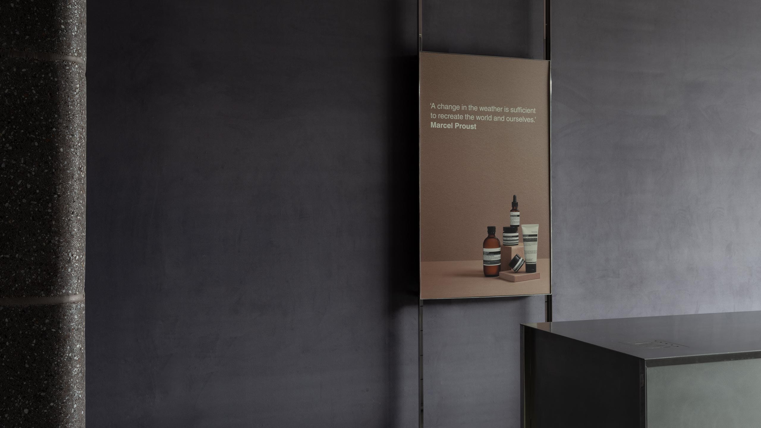A steel framed poster on the wall reads 'A change in the weather is sufficient to recreate the world and ourselves', a quote by Marcel Proust