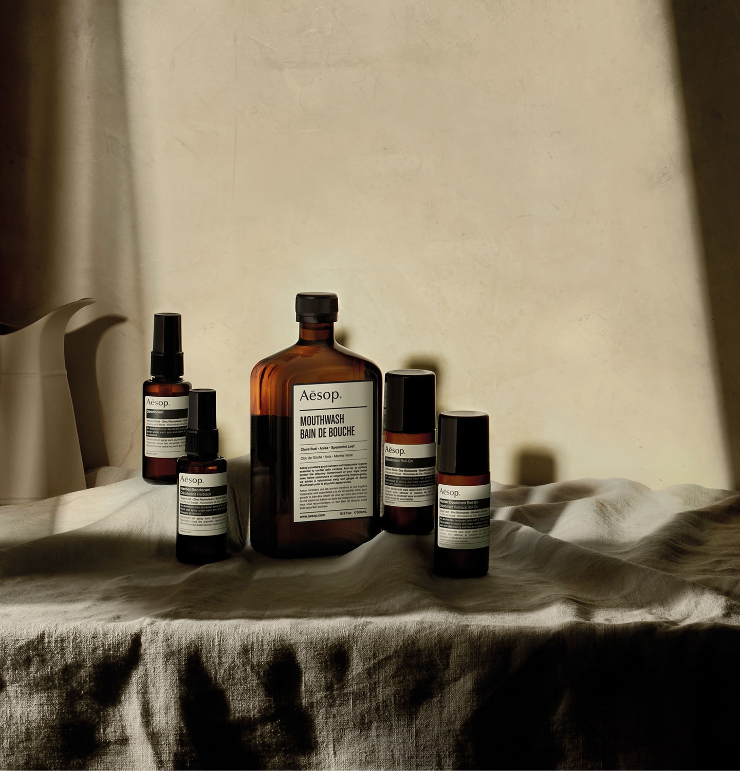 Aesop products arranged on a tablecloth, sitting in a shaft of light.