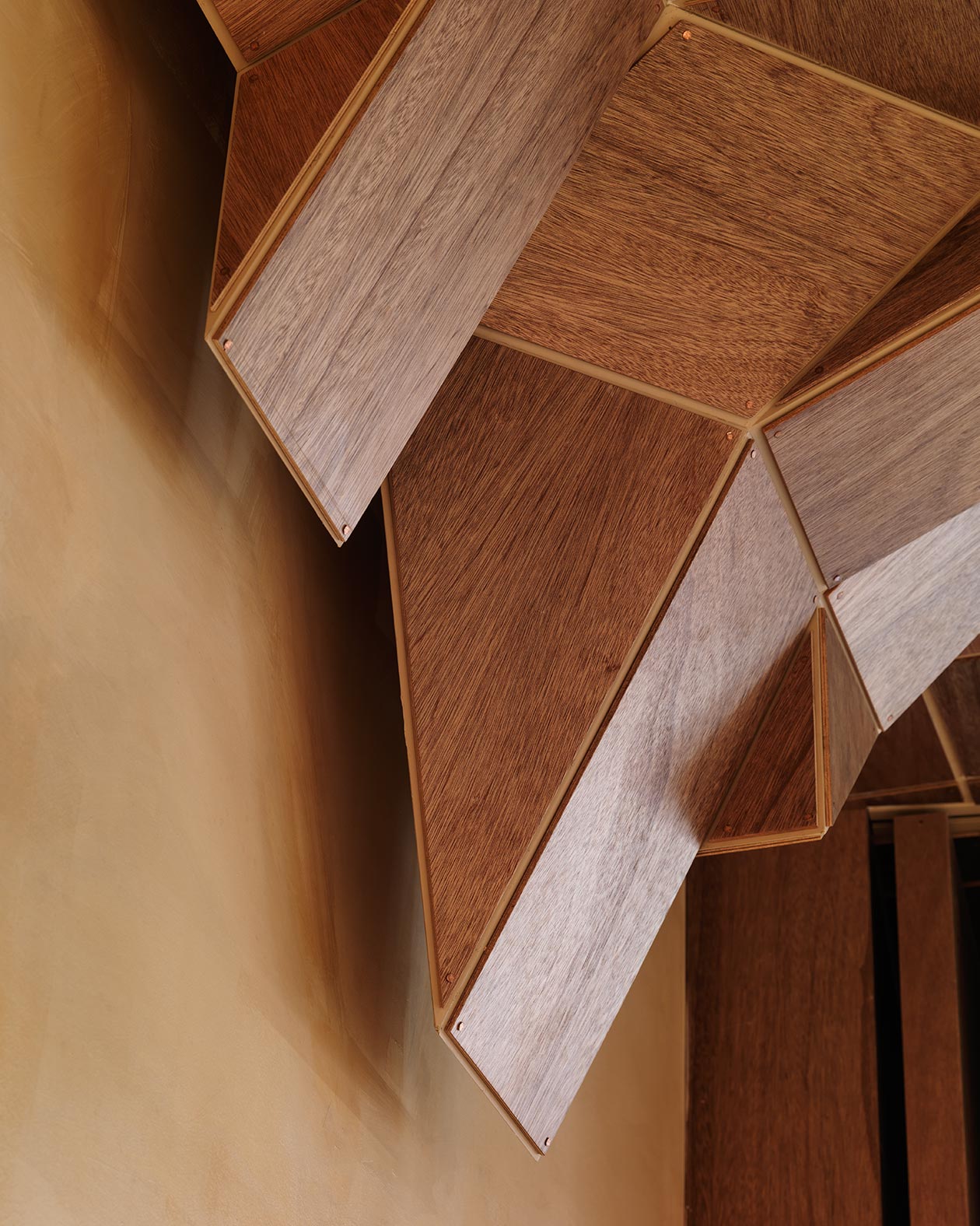 A close-up of the angular ceiling structure, crafted out of dark plywood.