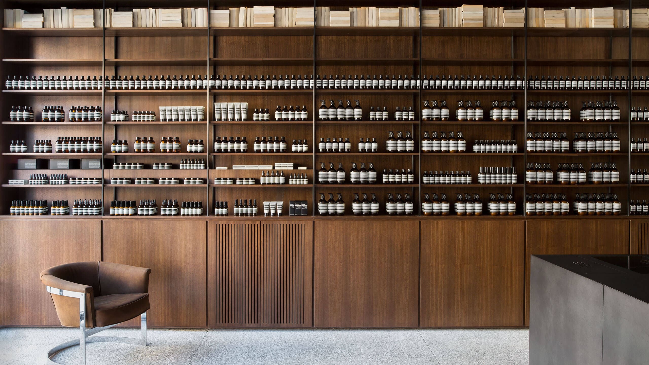 A wall-to-wall wooden shelf of Aesop product.