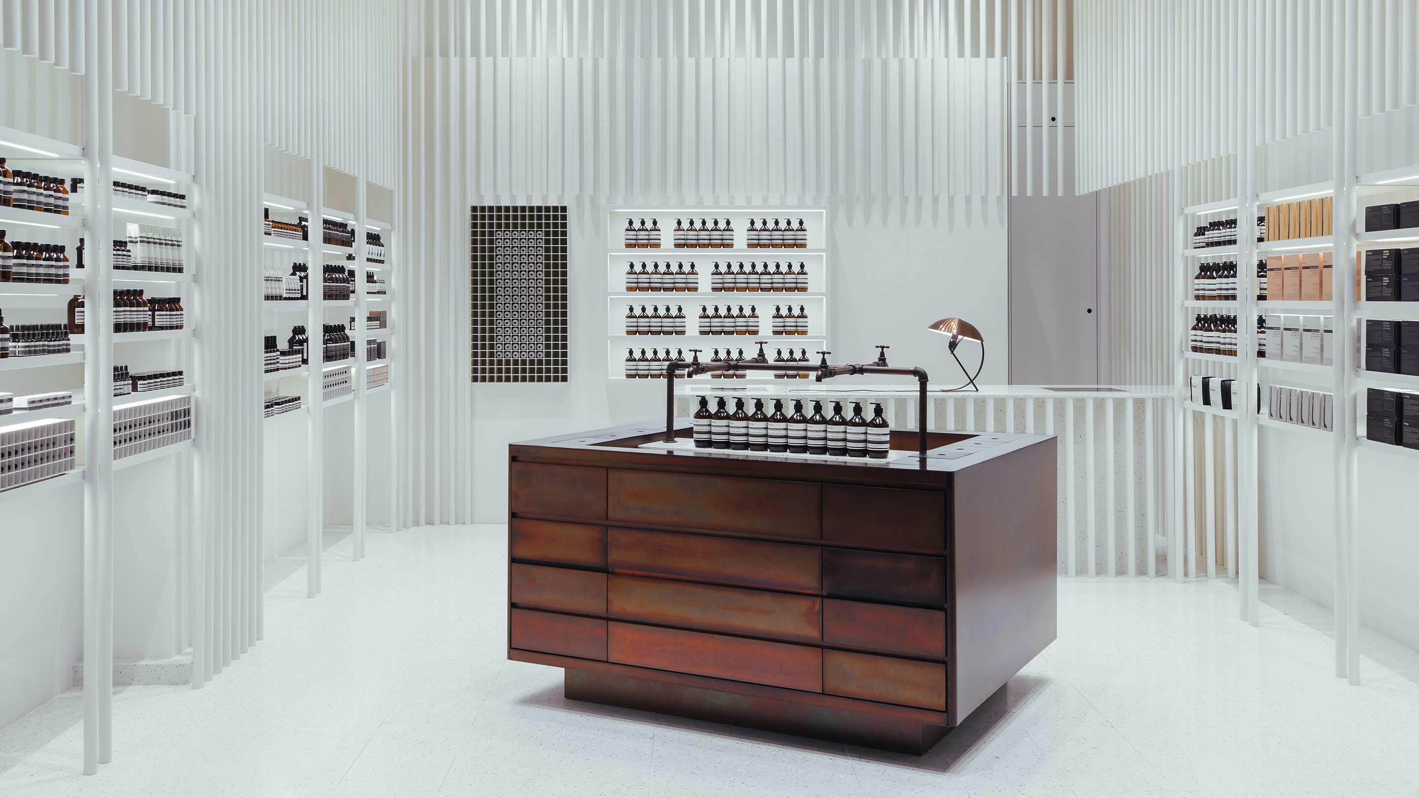 A freestanding dark-copper sink is juxtaposed against the bright white interior of the store.