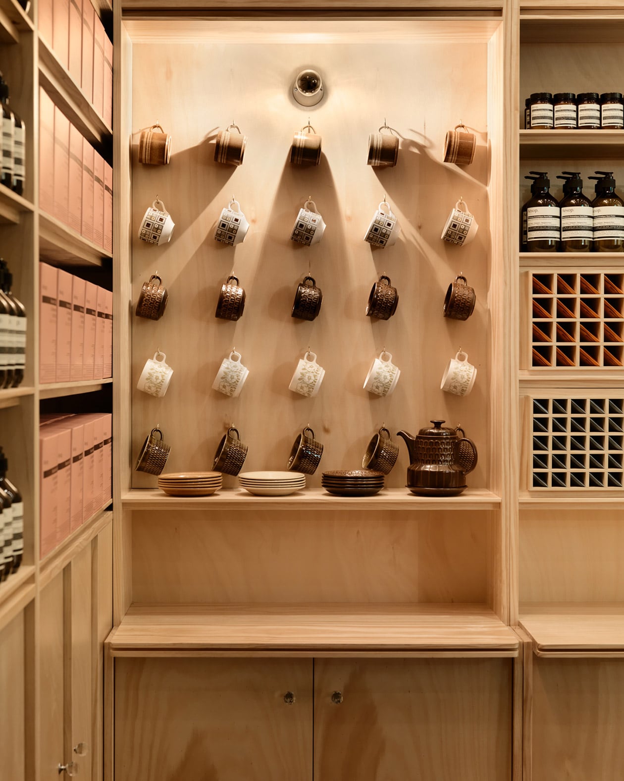 Five rows of tea cups hanging on hooks. This is accompanied by a brown teapot and several saucers that match the teacups.