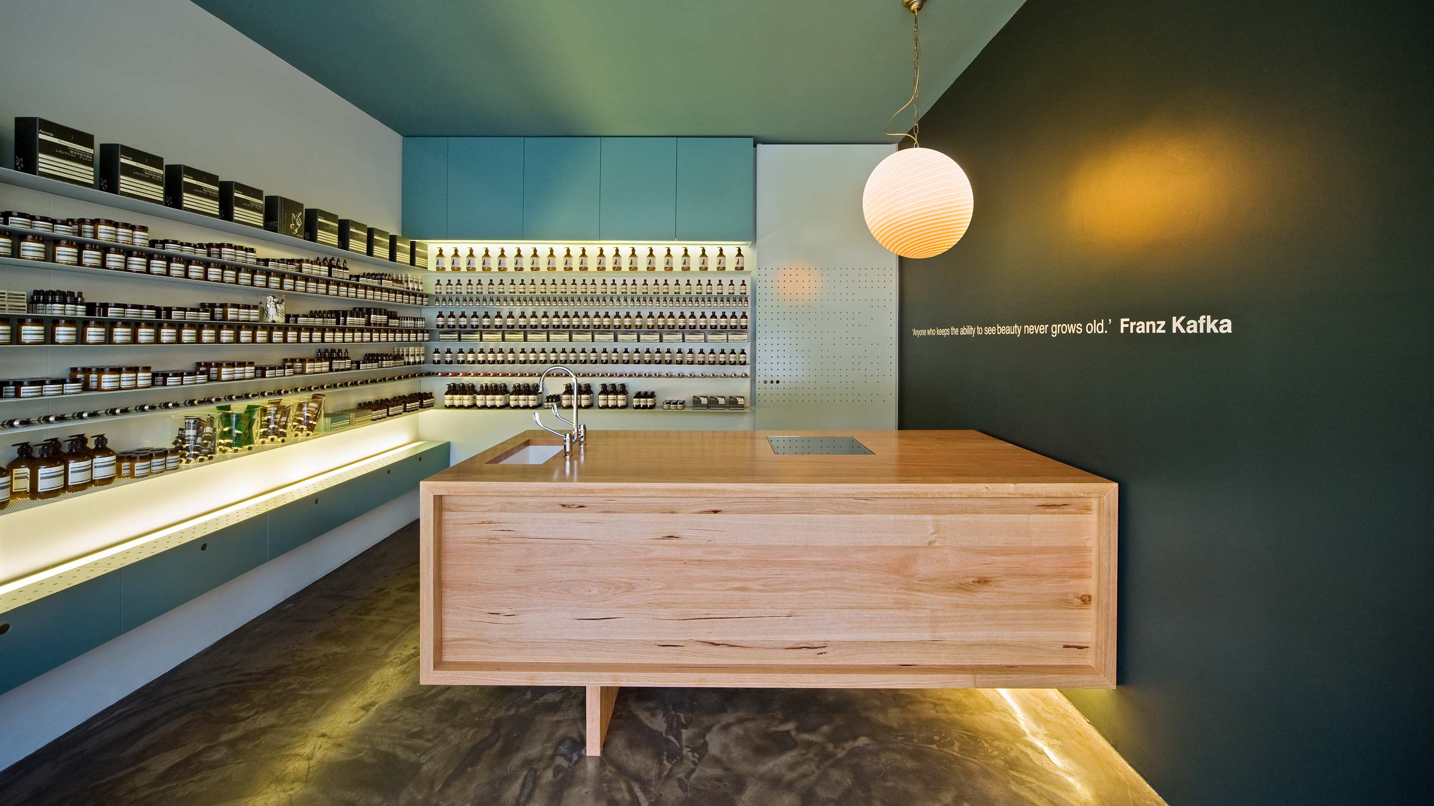 The stores interior featuring dark ocean green walls, and a natural timber customer service desk.