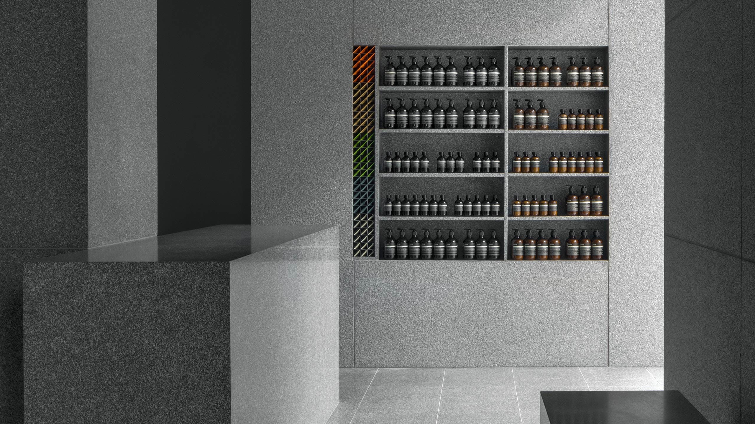 Concrete, stone sinks featuring Aesop product displayed on stone shelving. 