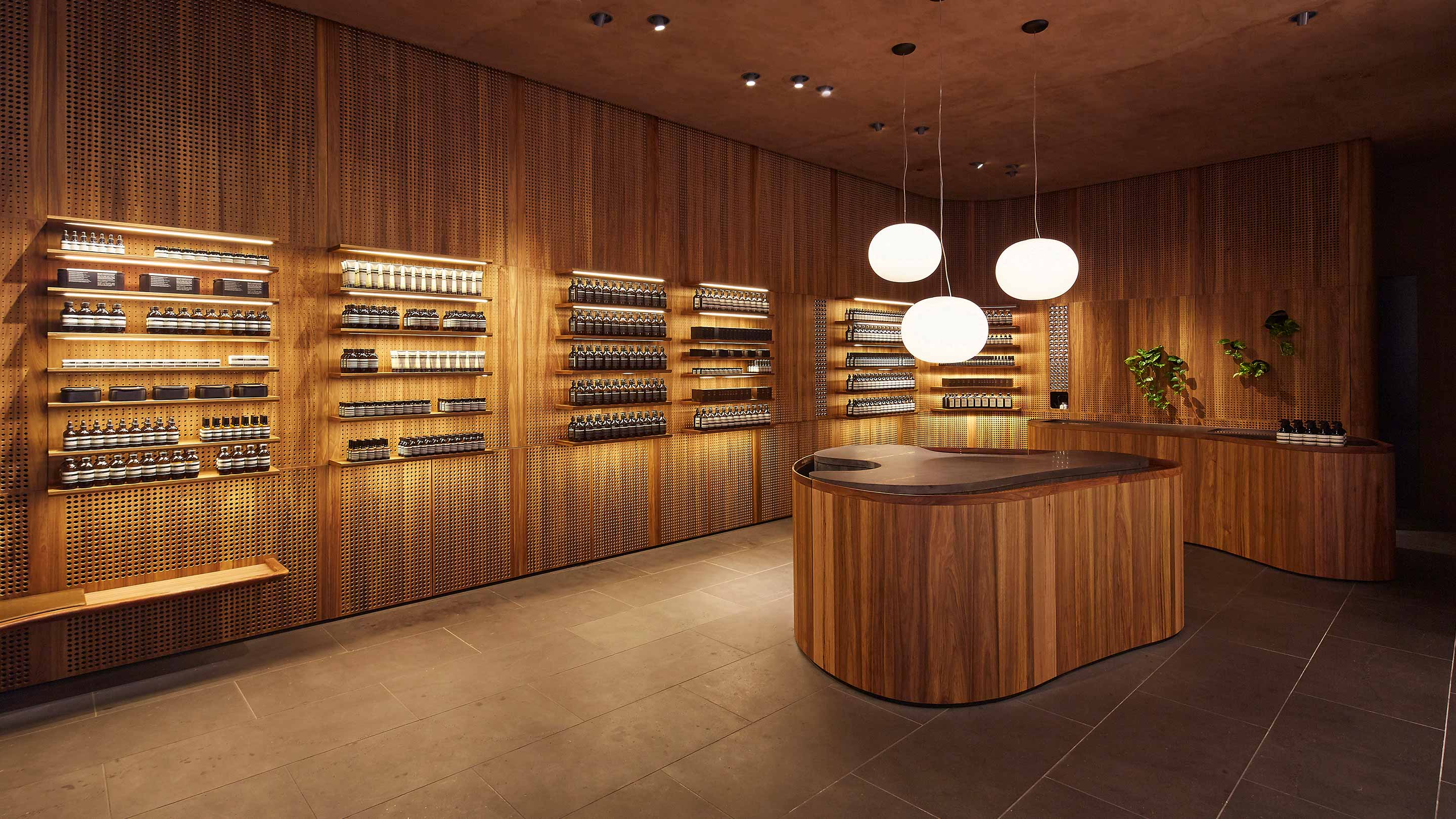 Dark wooden walls line the interior; the floors are a dark grey tile. The curved service desk has three large light fixtures suspended above it.