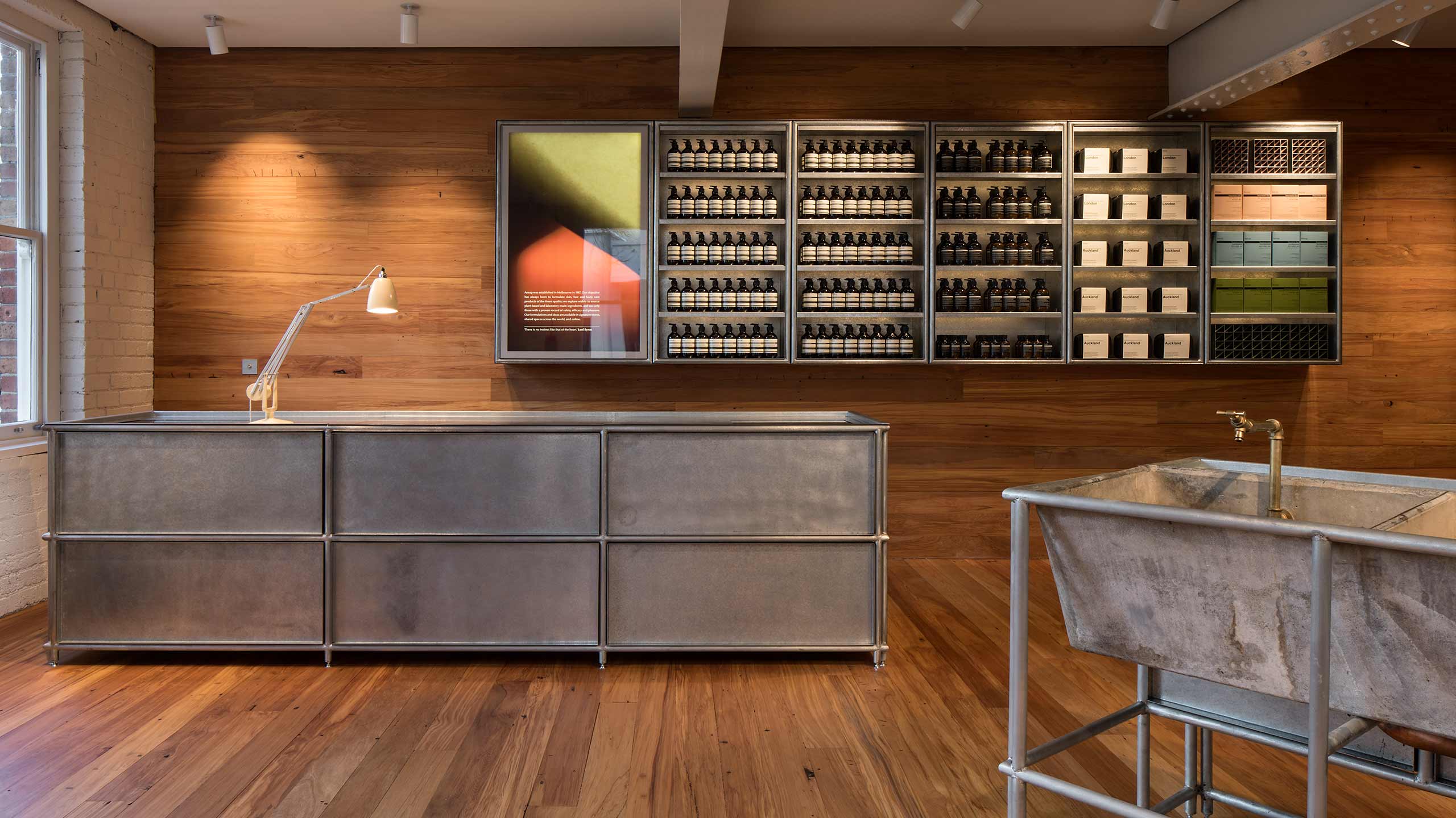 The main customer service desk crated from brushed steel. The shelves behind the counter are adorned with Aesop products.