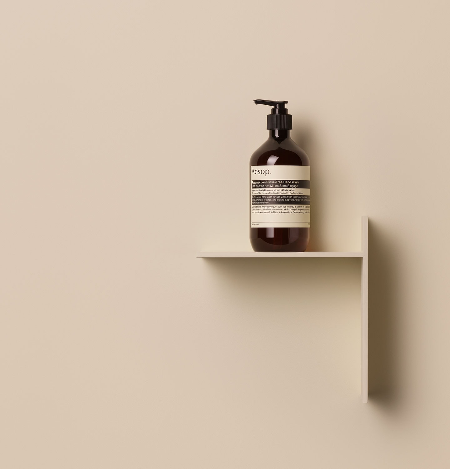 Aesop Resurrection Rinse-Free Hand Wash in amber pump bottle arranged on a wooden object in a beige background