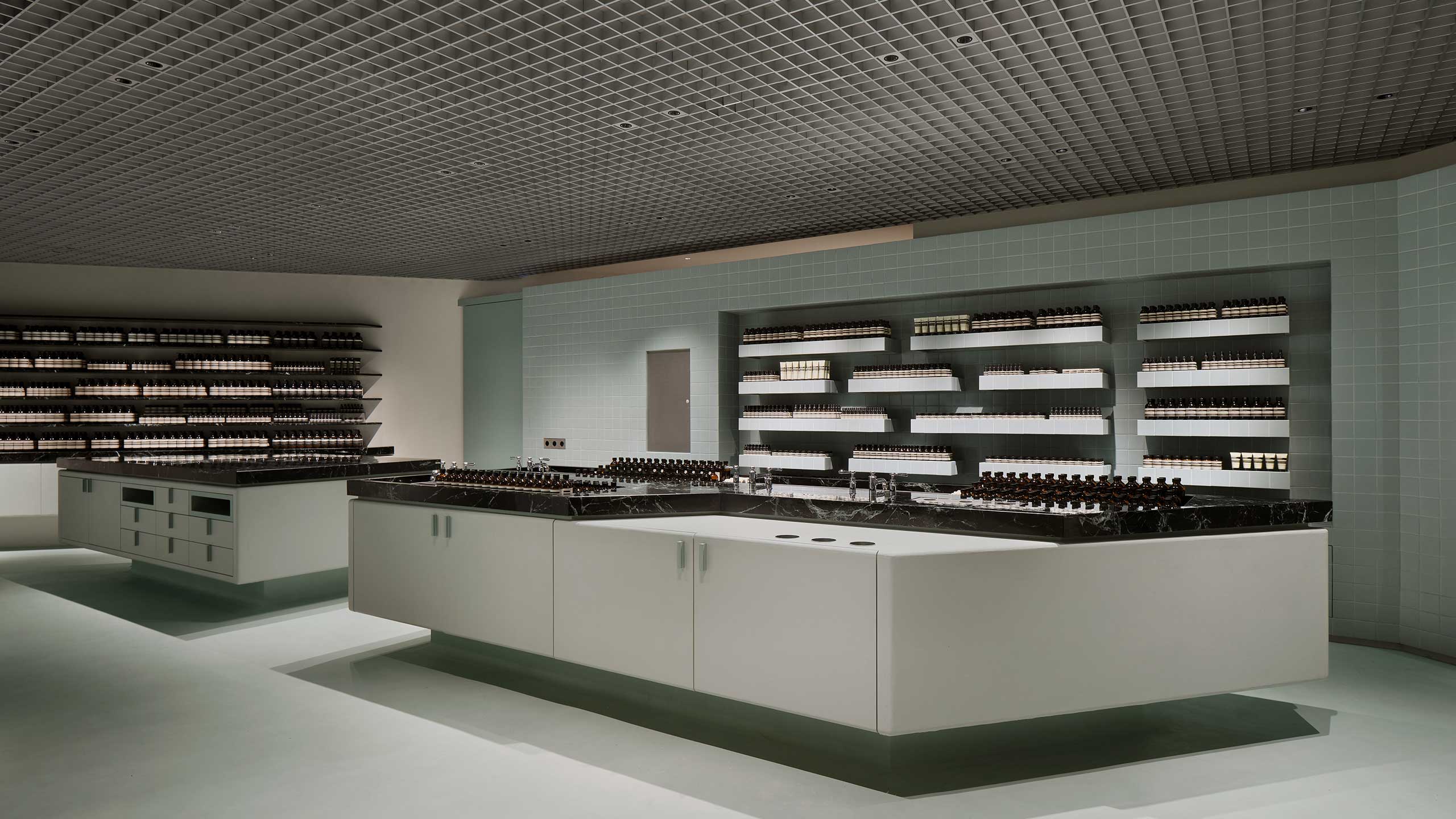 Matte vibration-finished stainless steel contracts with the ceramic-tiled walls, showcasing Aesop’s formulations for the skin, hair, body and home. 