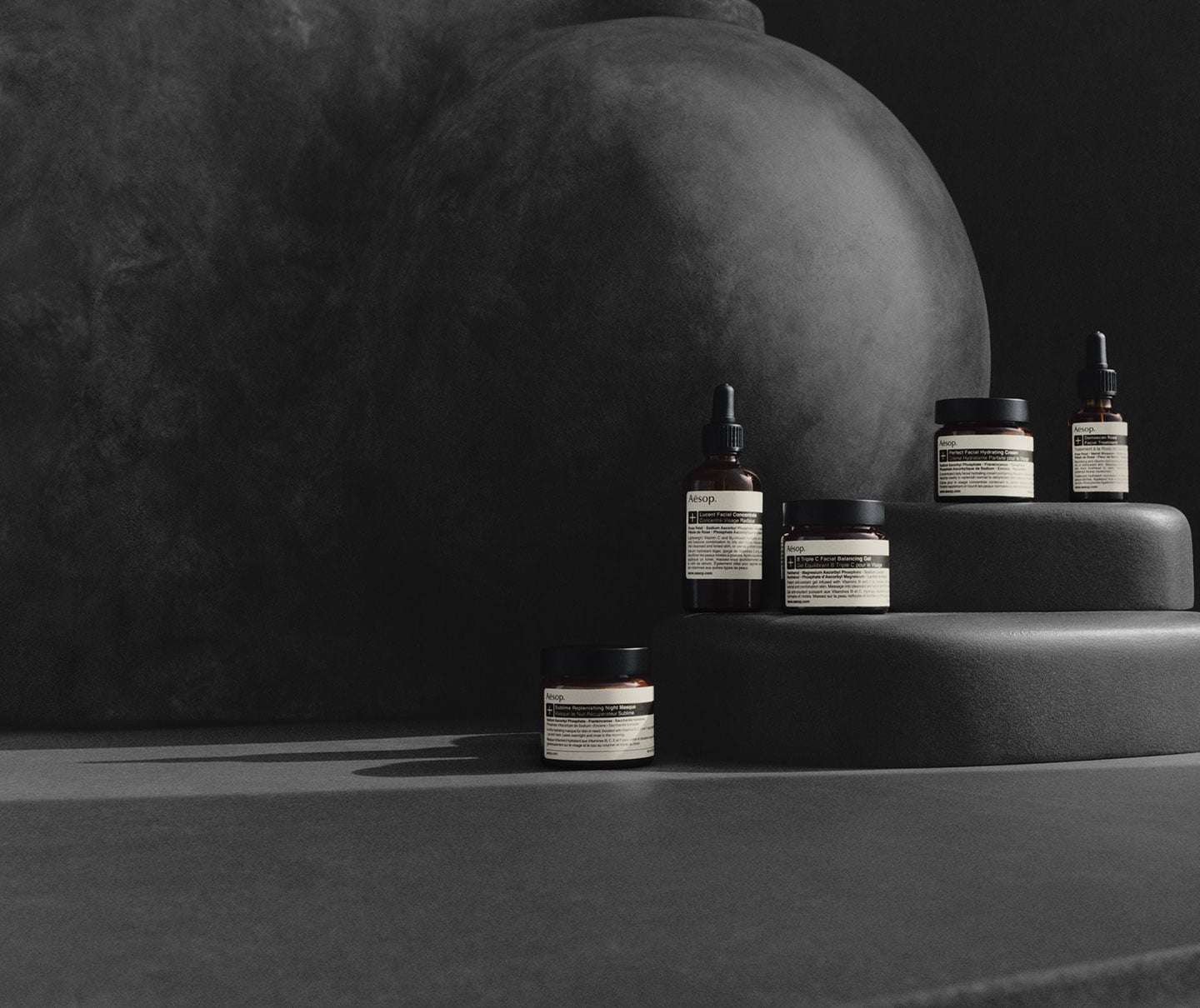 Aesop products sitting in front of a dark backdrop.
