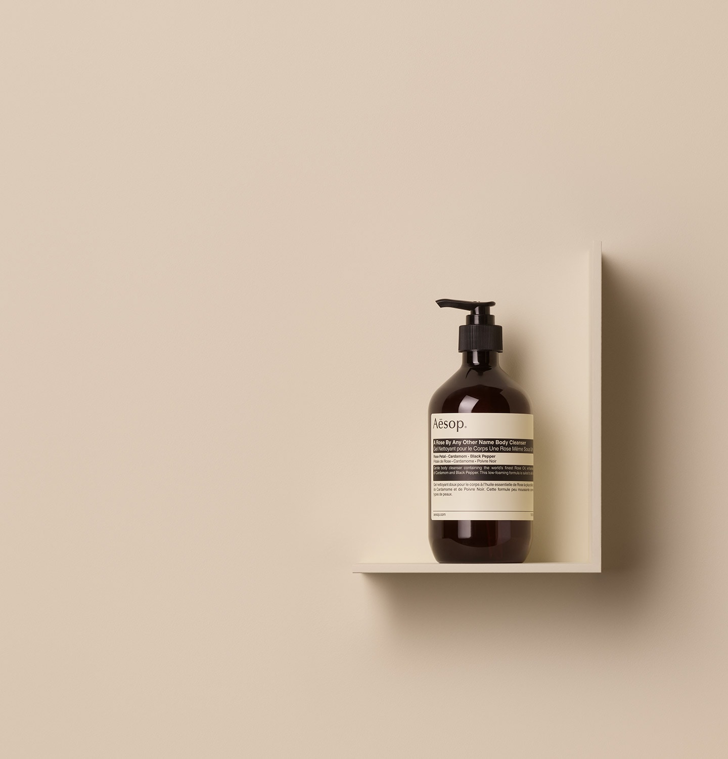 Aesop A Rose By Any Other Name Body Cleanser in 500ml amber pump bottle placed on a shelf in a beige surface