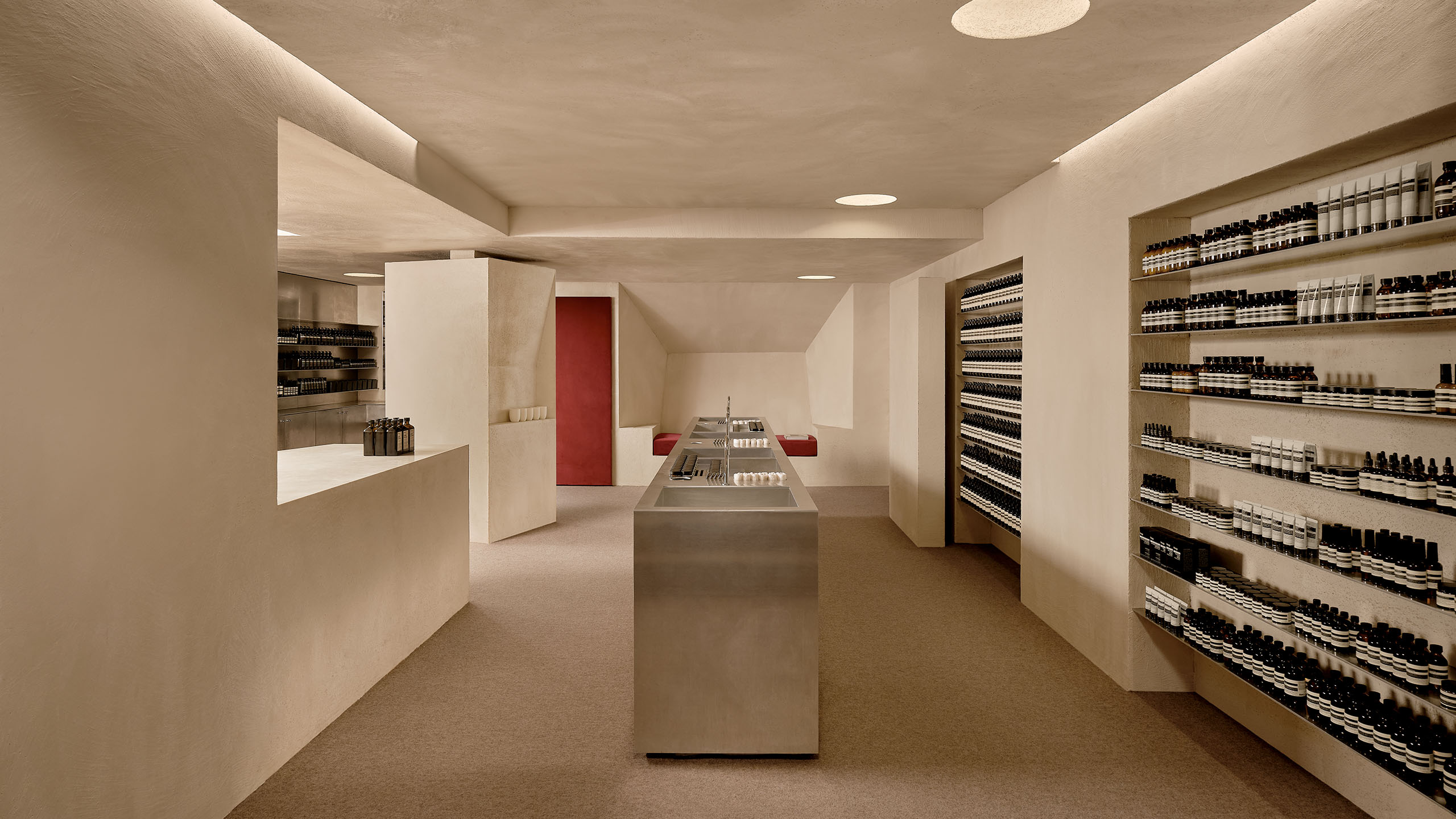 store interior featuring grey walls, grey counter sinks in the foreground, and red door in the background