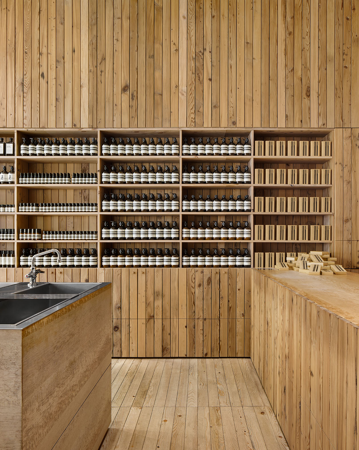 A wall of shelves made from reclaimed timber holding Aesop product