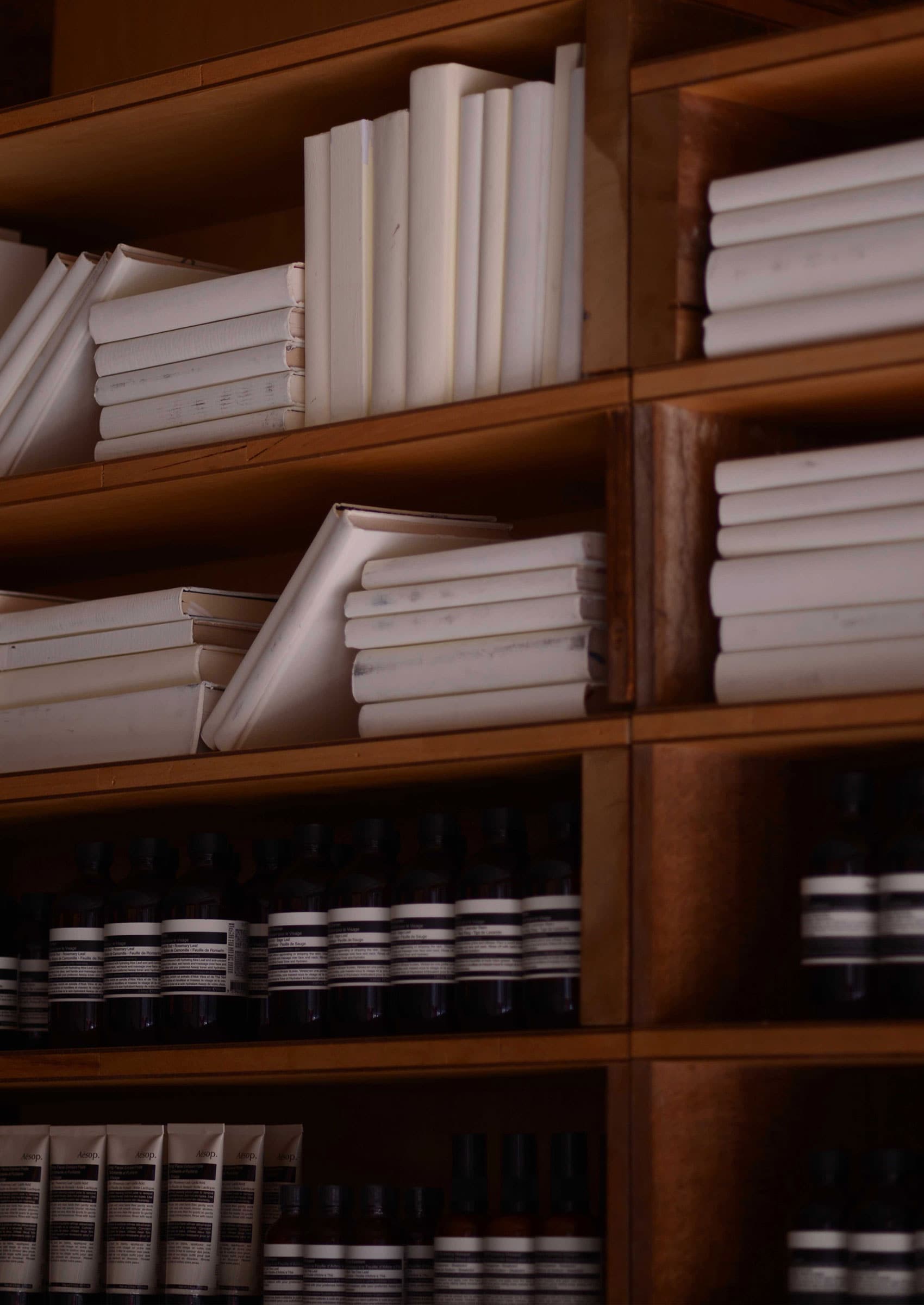 Shelves containing books and a range of Aesop products in amber bottles and cream tubes.