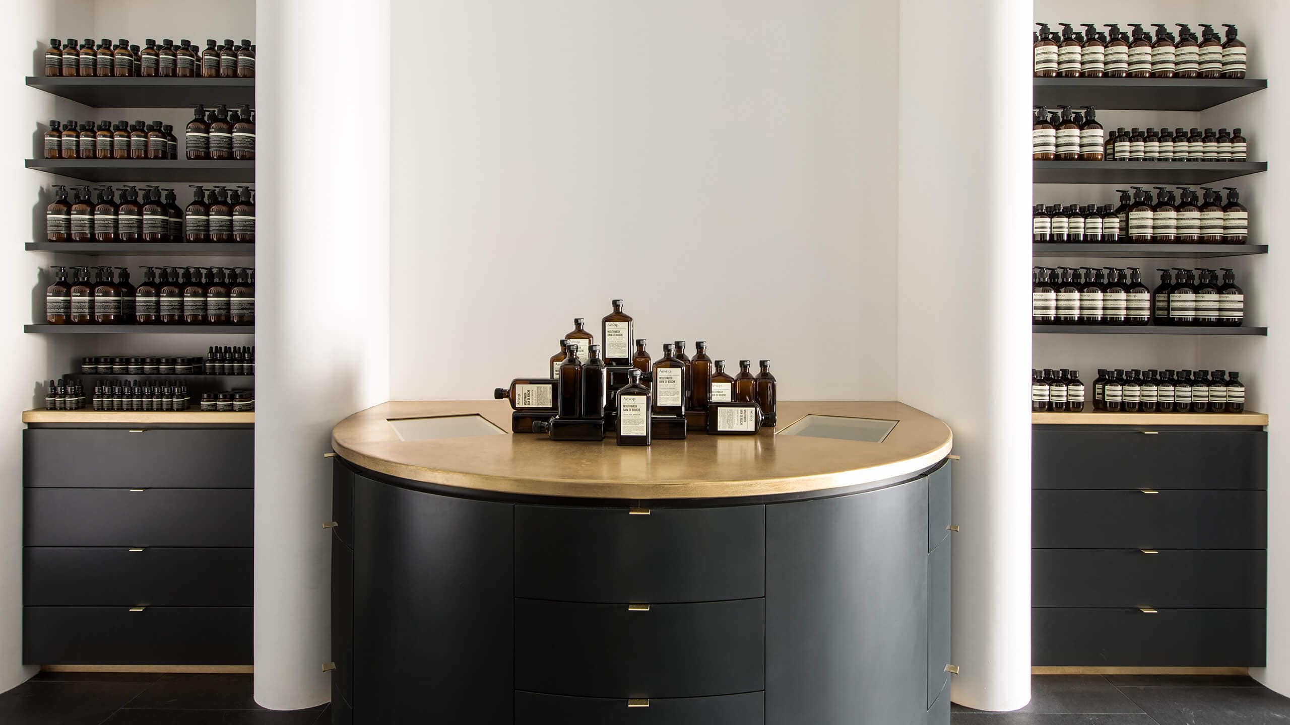 Aesop Studio City store interior, featuring an arrangement of Mouthwash bottles on a golden-topped counter.