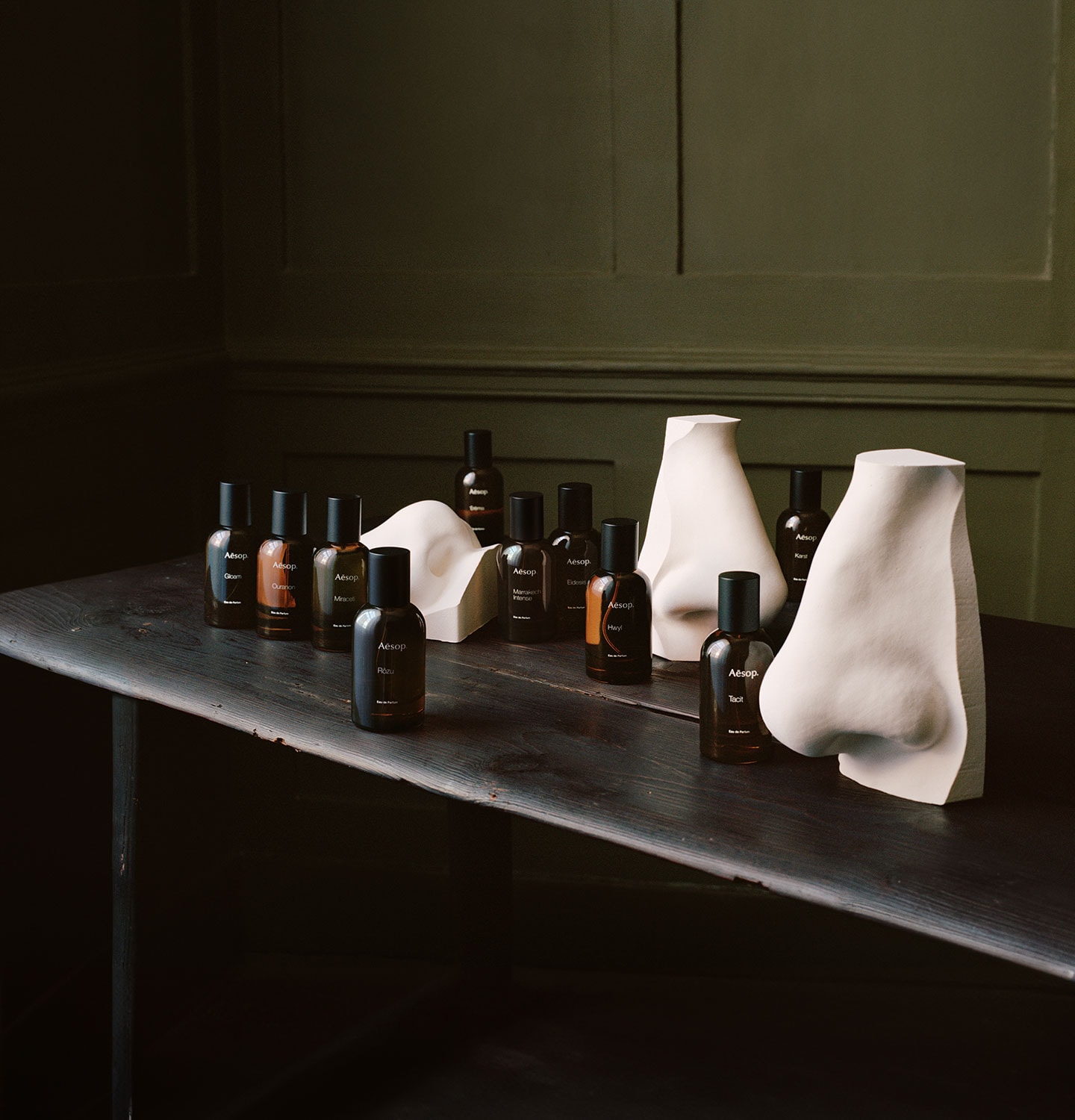 Aesop fragrances in amber bottles placed next to nose sculptures