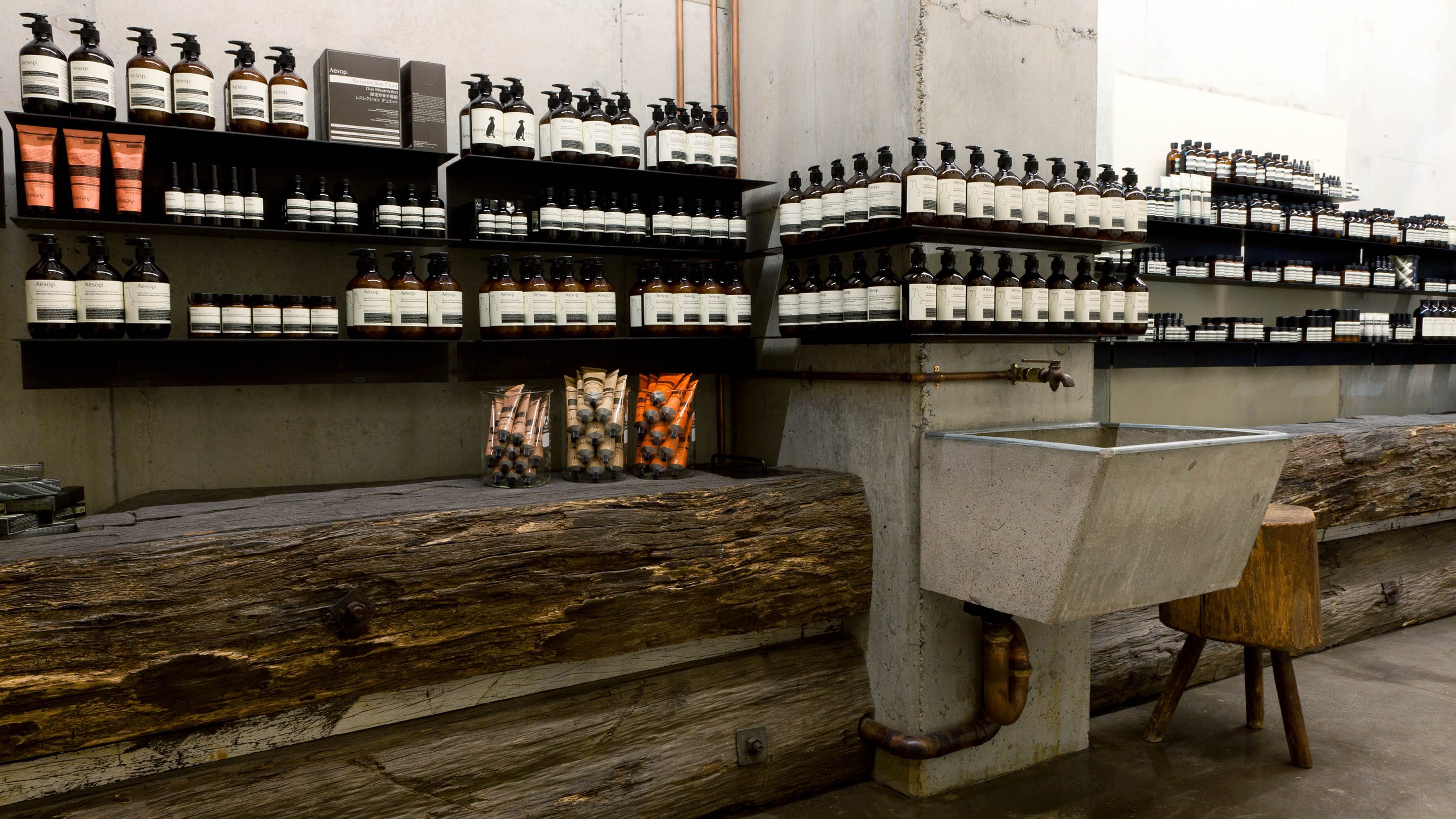 Recycled wharf wood makes the counters that line the store. There is a large concrete laundry basin with brass fixtures.