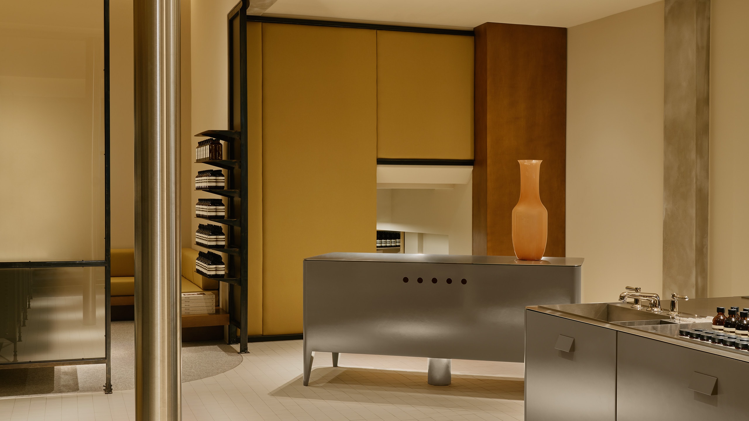 Aesop Sendlinger Strasse store interior featuring metal display cabinet and basins, contrasted against the stone and wood textures.
