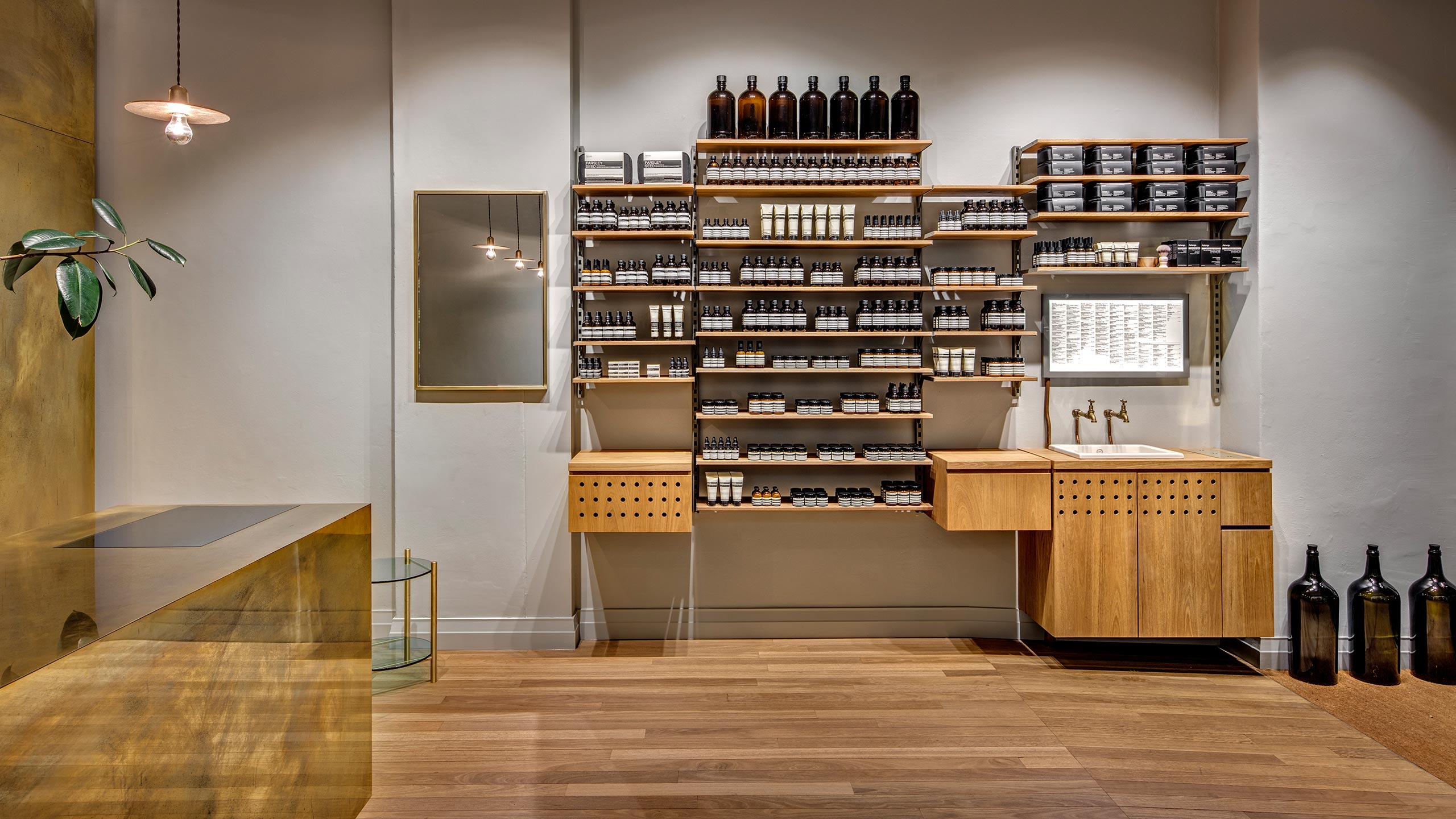 A wood constructed shelving unit that displays several Aesop products