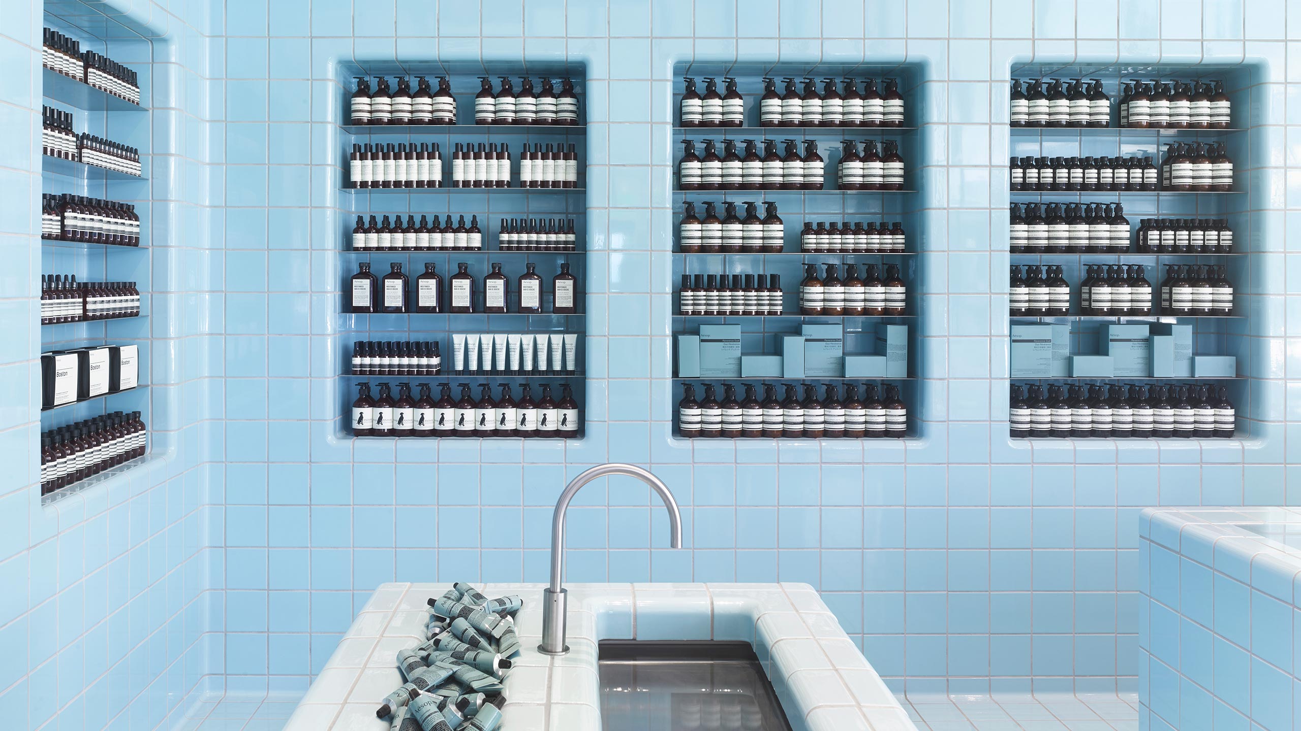 A light-blue tiled wall featuring a sink with a steel tap mimicking the look and feel of a swimming pool. 