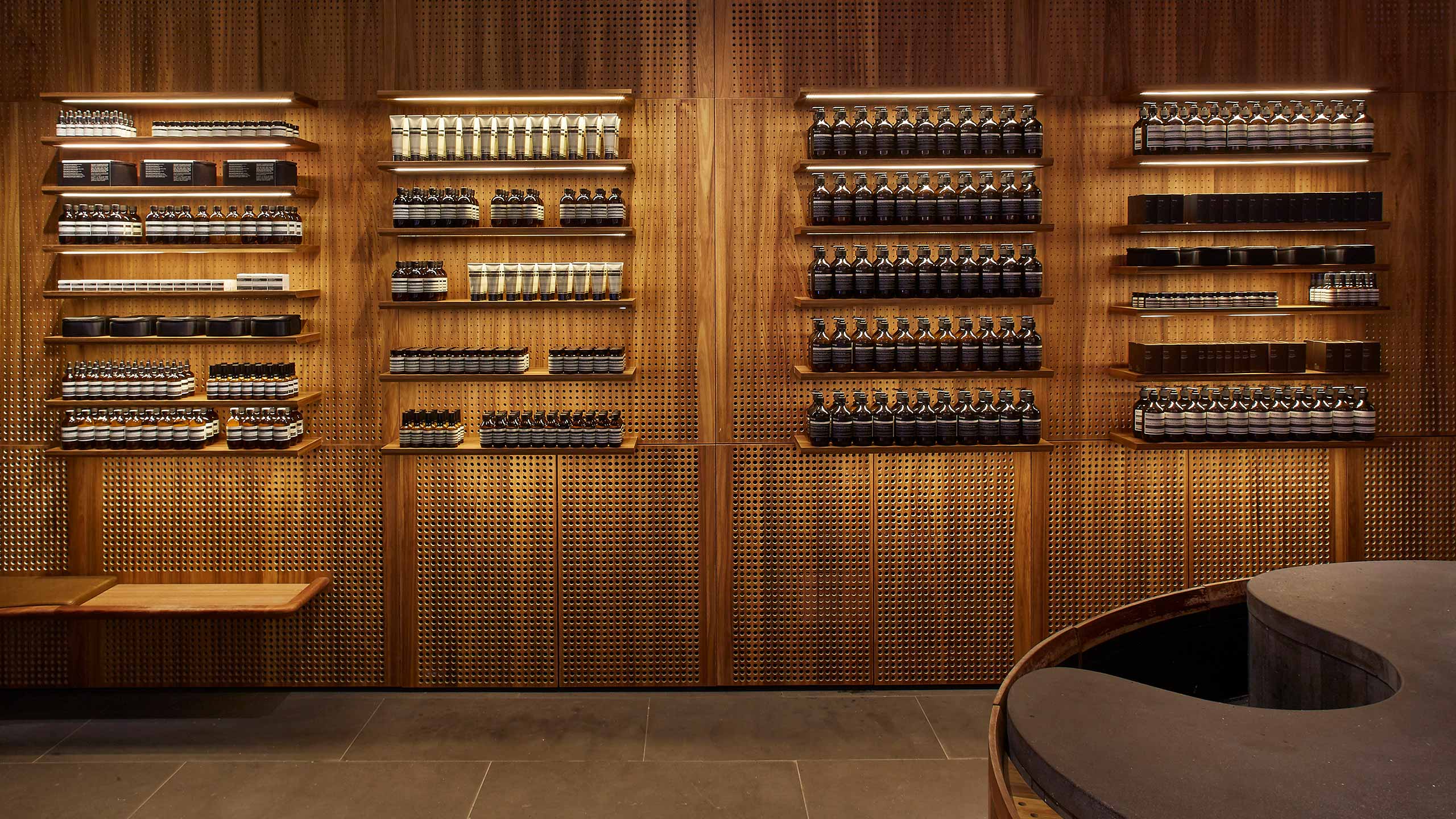 A dark wall that features twenty product shelves. Each shelf features its own light fixture.