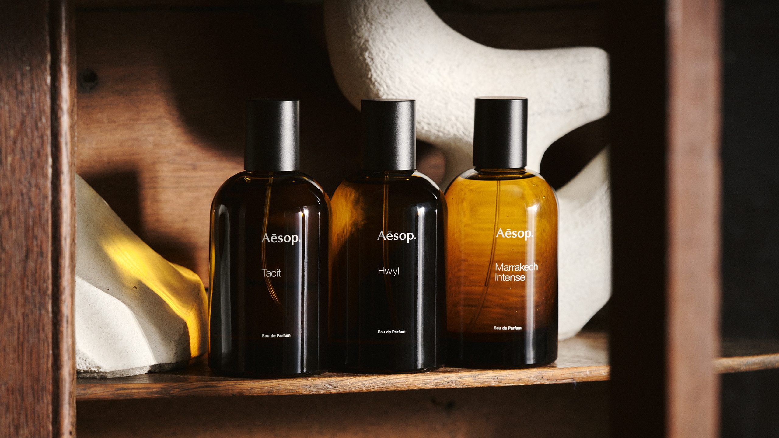 Three 100mL amber glass bottles on the shelf of a wooden cabinet.