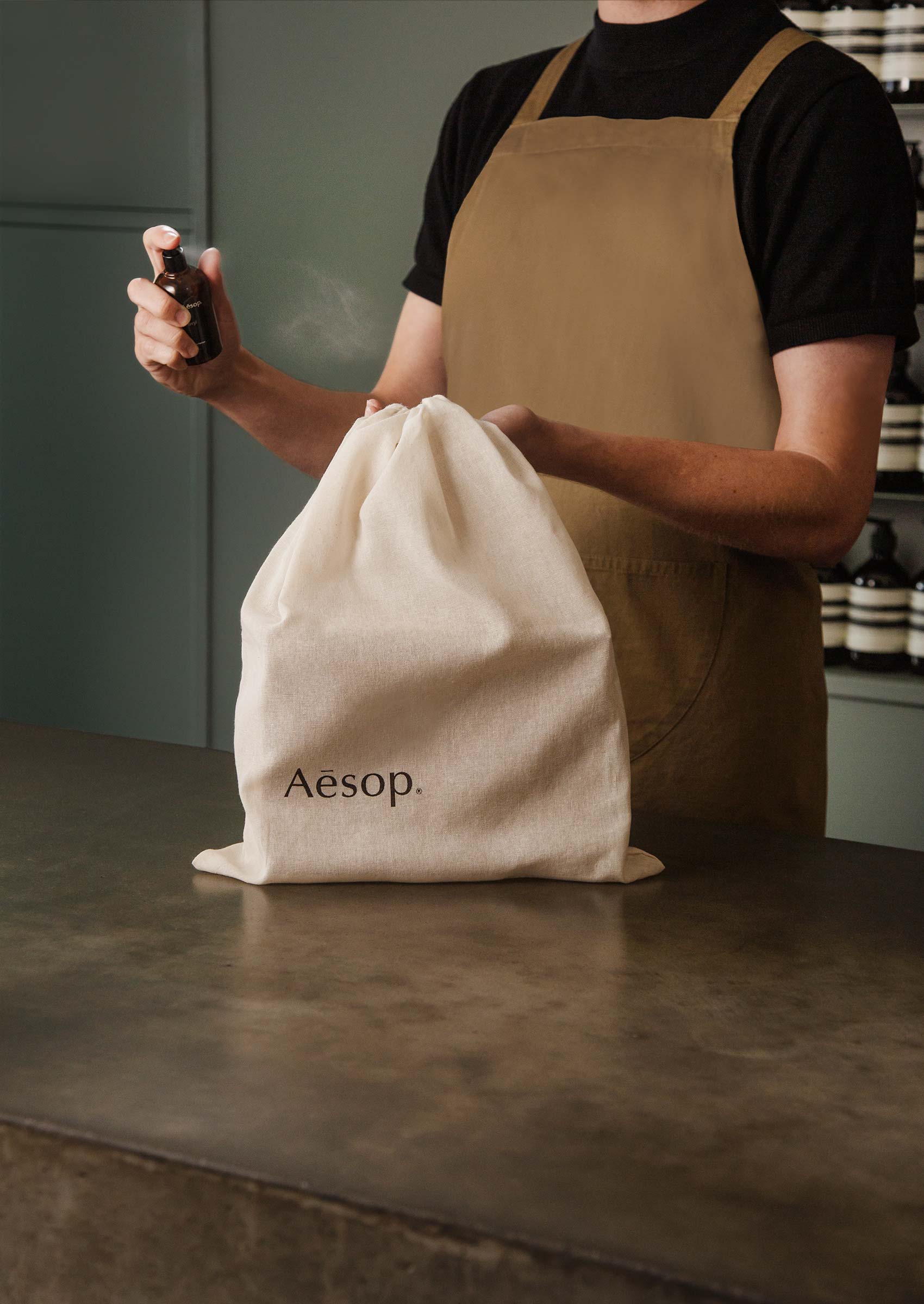 An Aesop consultant spritzing a cotton bag with fragrance.