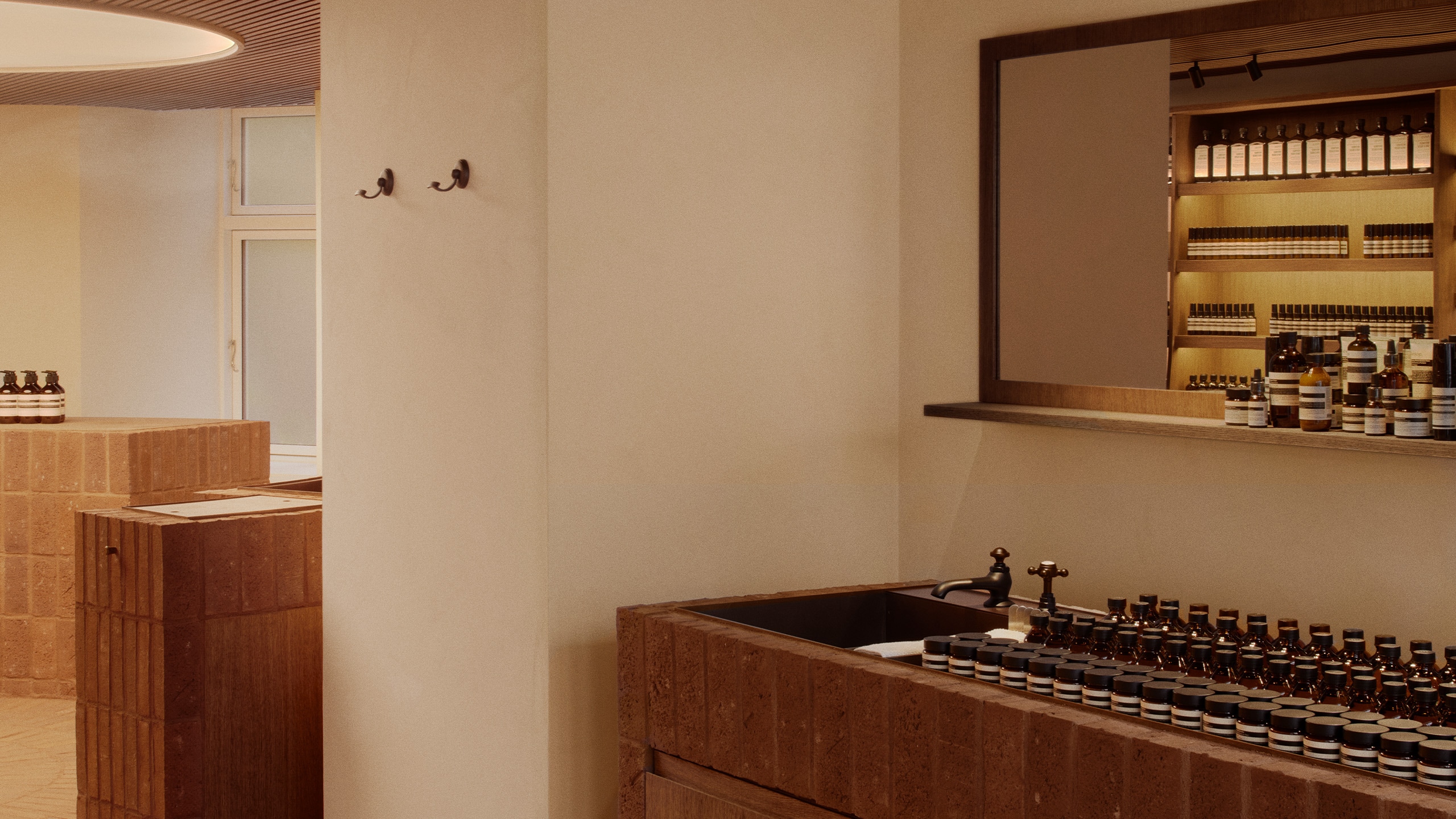 Aesop Kronprinsensgade store interior basin with a mirrored shelving unit displaying a range of products.