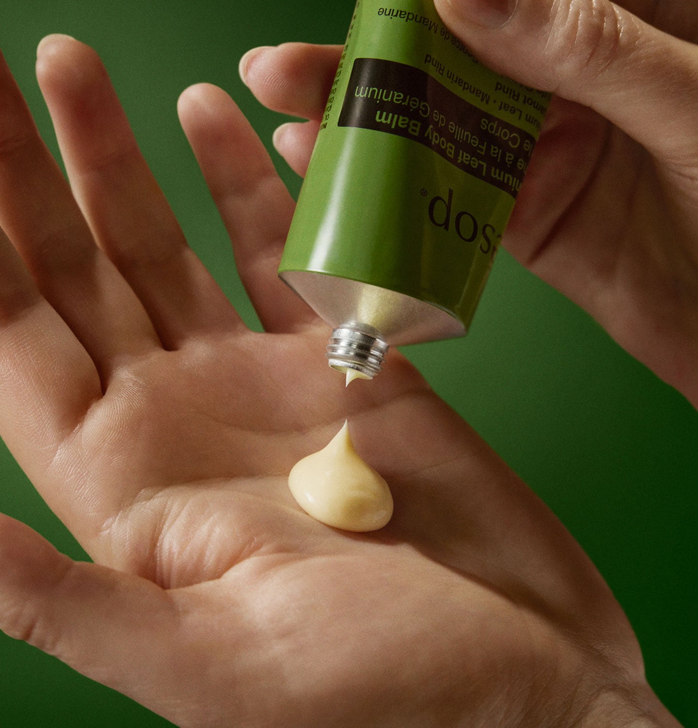 A hand pumping Geranium leaf body balm on a palm